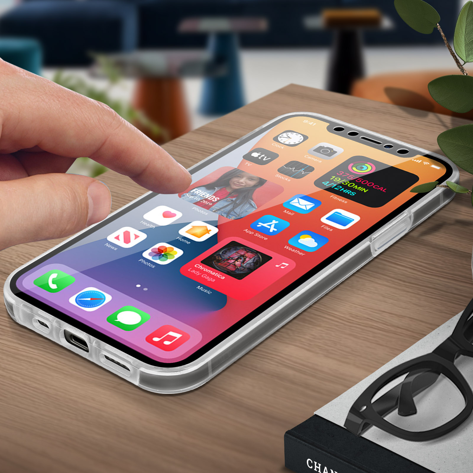 Hand die een telefoonscherm met apps aanraakt. Tafel met plant en bril. Neutrale achtergrond met houten tafel.