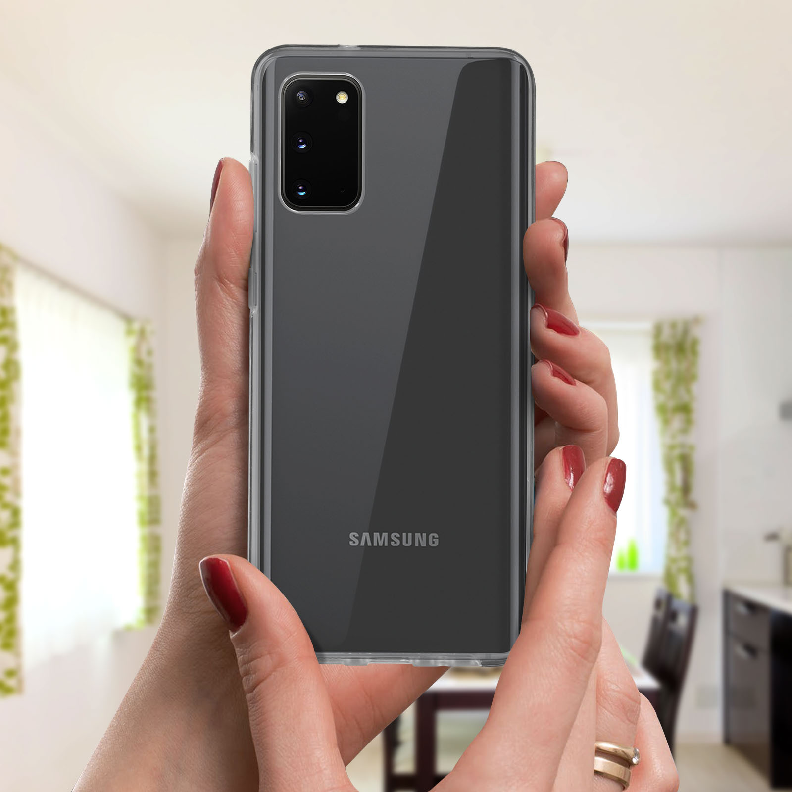 Handen die een zwarte Samsung-telefoon met een doorzichtige hoes vasthouden. De achtergrond toont een kamer.