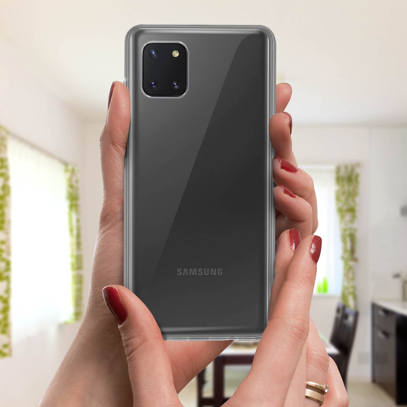 Un telefono in una custodia trasparente, tenuto in mano. Lo sfondo è una cucina.