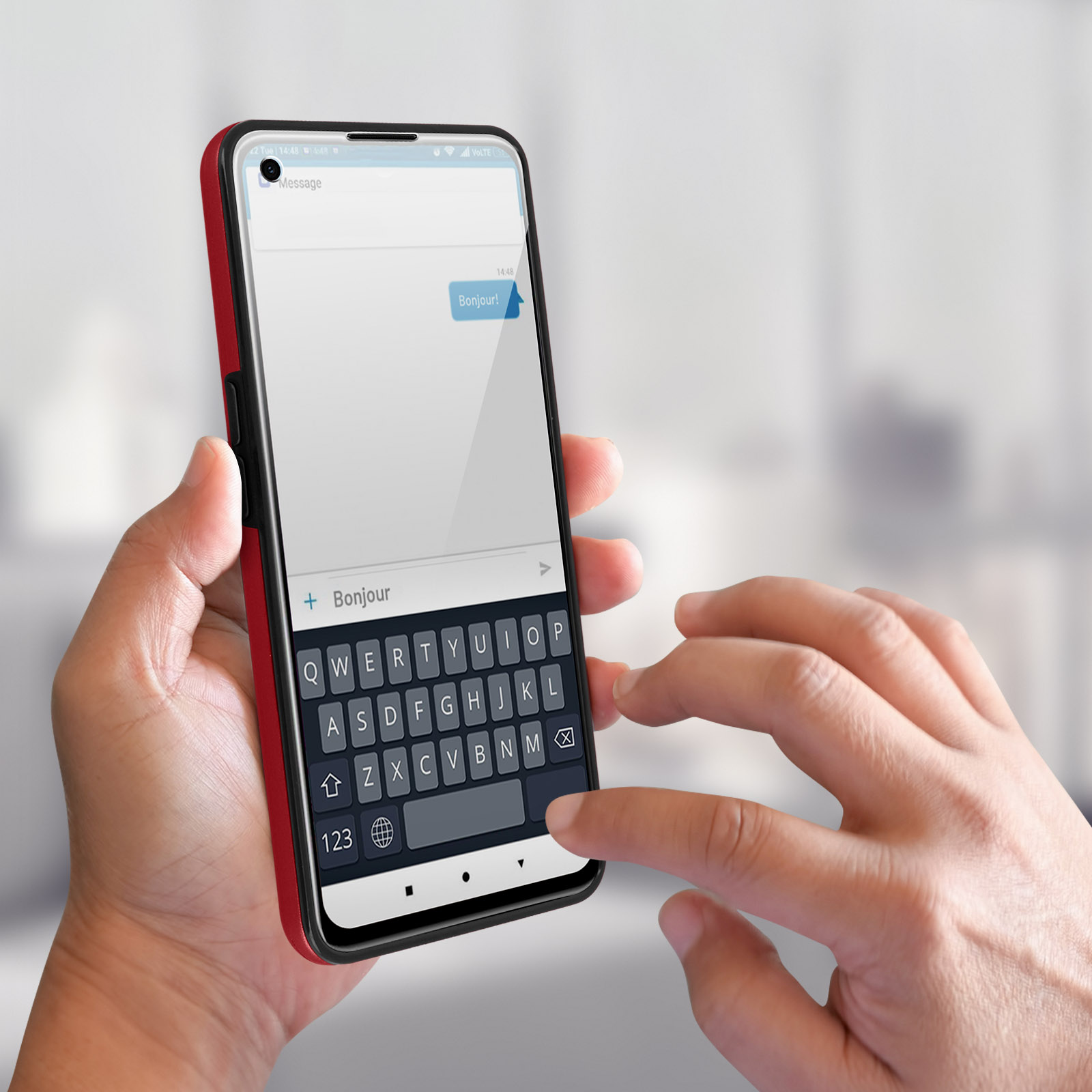 Mano che tiene un telefono che mostra un messaggio in francese, con una tastiera. Lo sfondo è sfocato.