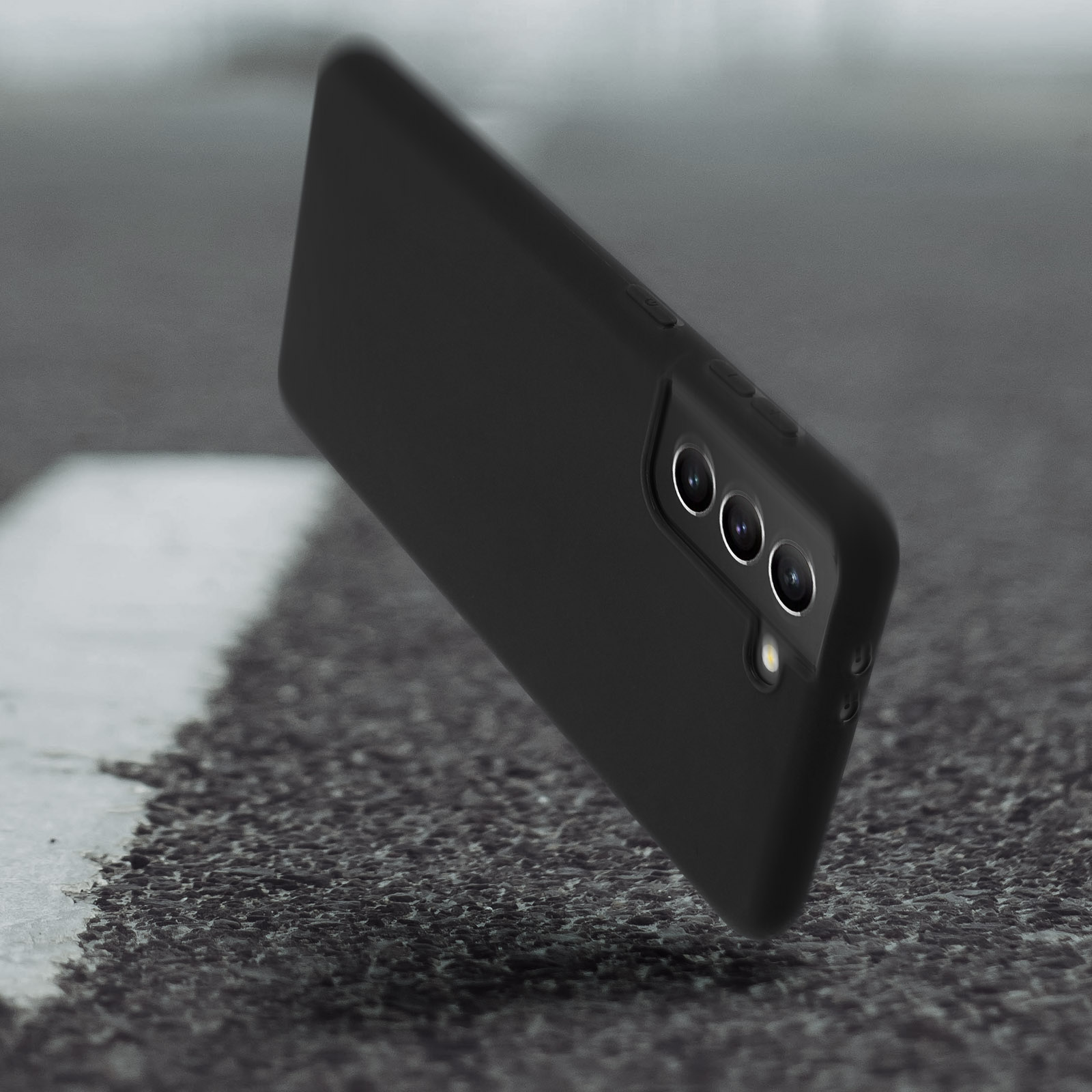 Custodia nera per telefono su superficie strutturata. Tre lenti della fotocamera visibili.