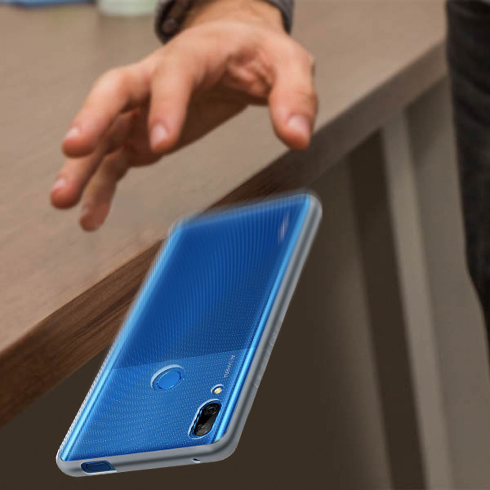 Un telefono sta cadendo da un tavolo. Il telefono è blu e ha una custodia.