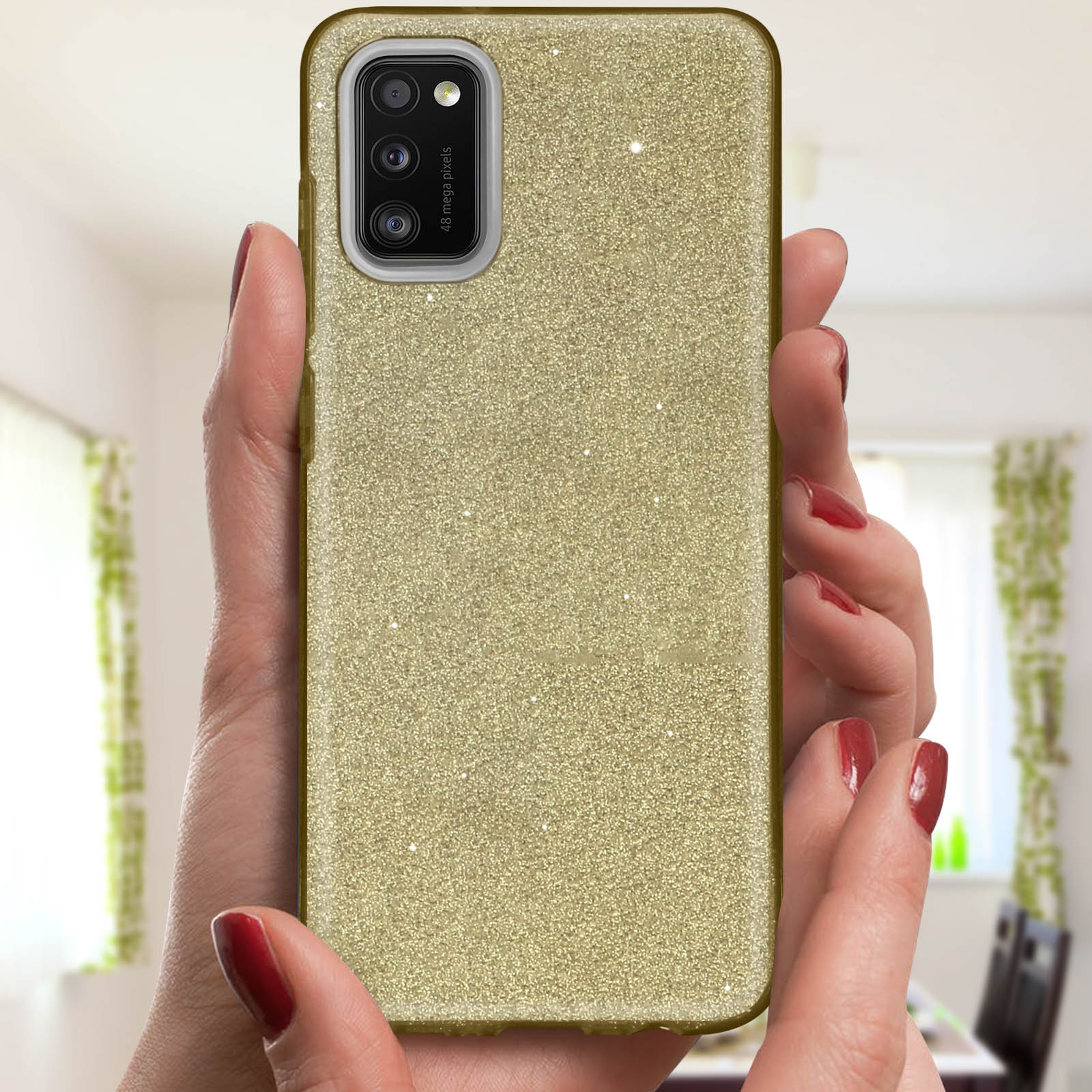 Een hand die een gouden glitter telefoonhoesje vasthoudt. Rode nagellak is zichtbaar.