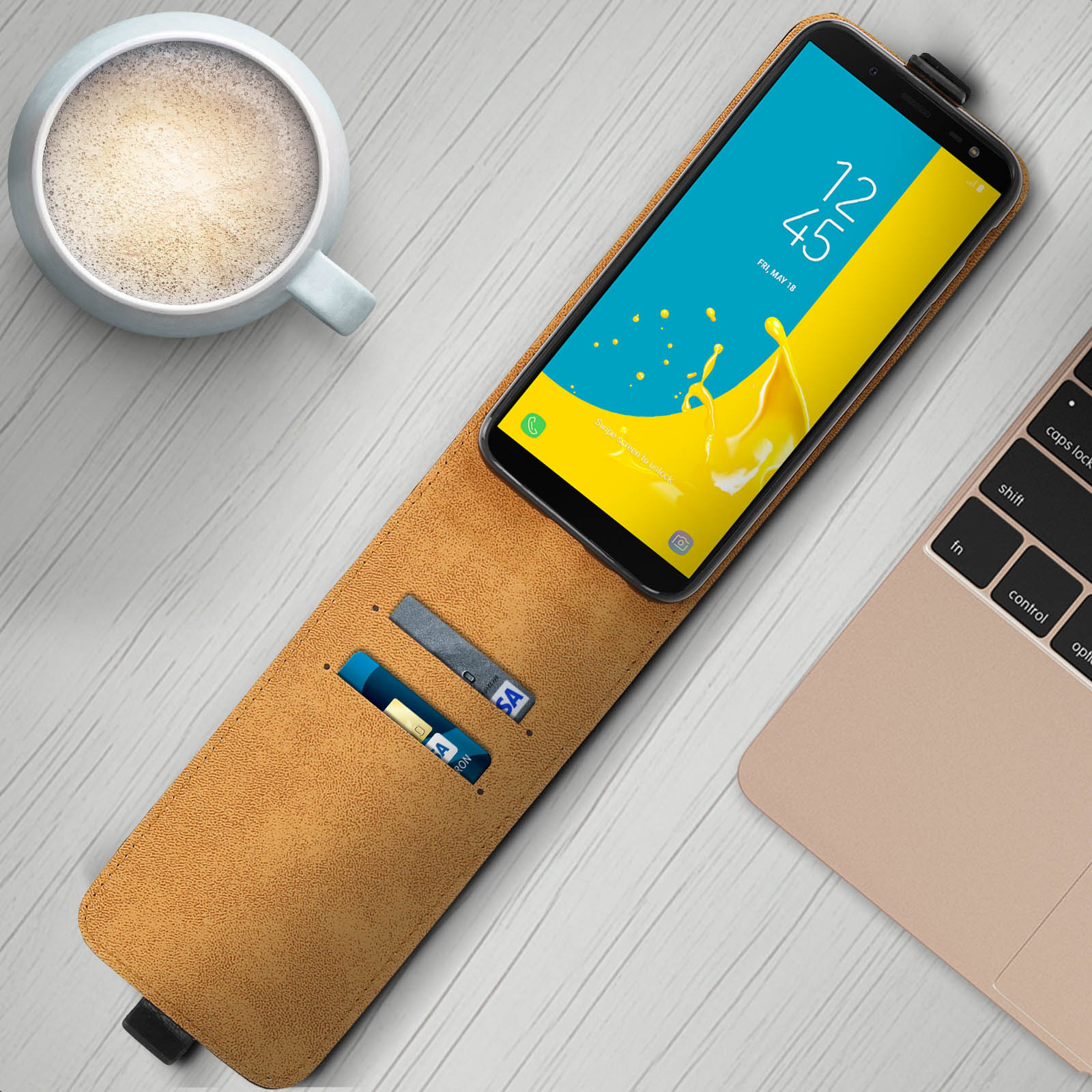 Telefon in einer braunen Hülle mit Karten. Tasse Kaffee und Laptop auf dem Tisch.