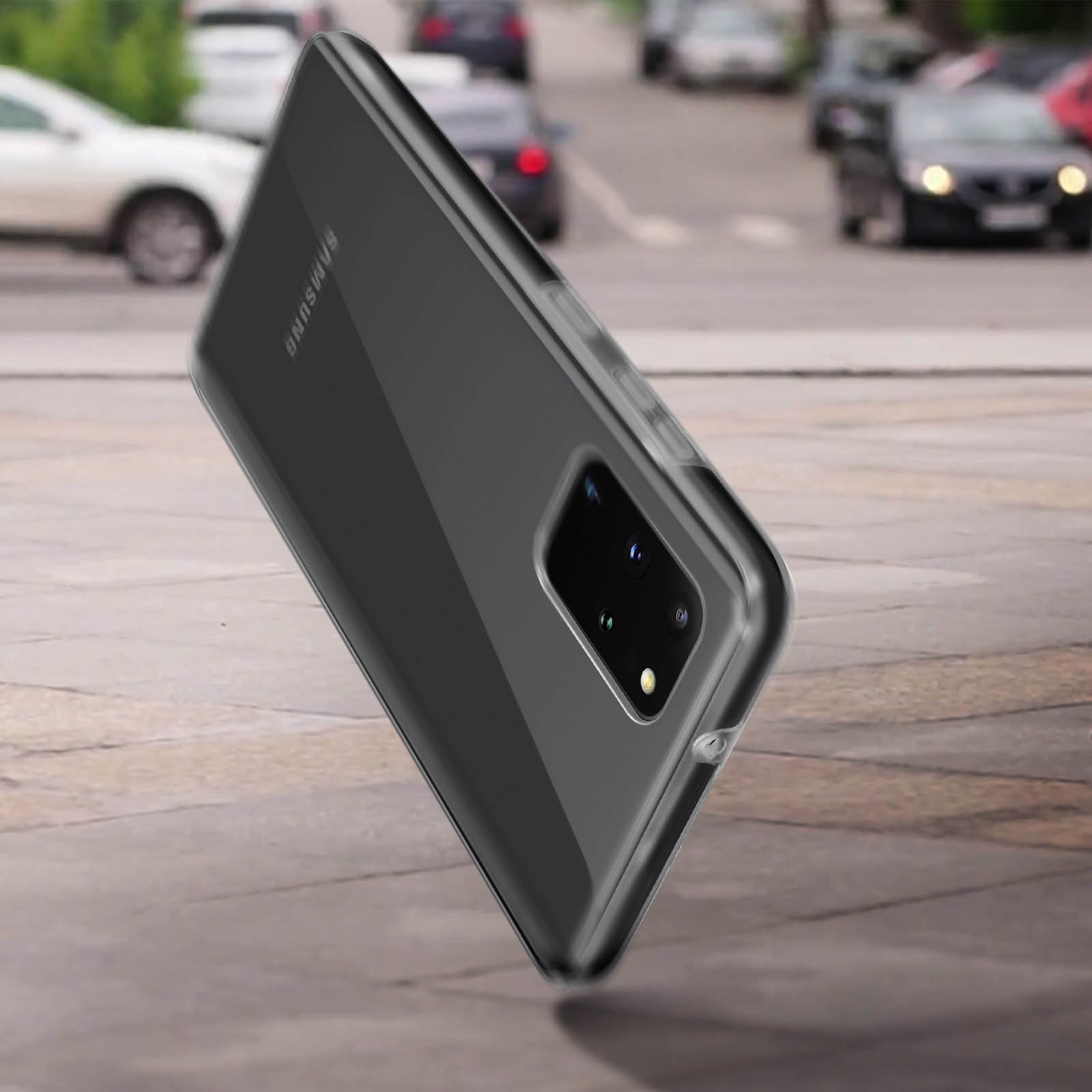 Un téléphone noir avec un étui transparent est posé sur un trottoir, des voitures sont en arrière-plan.