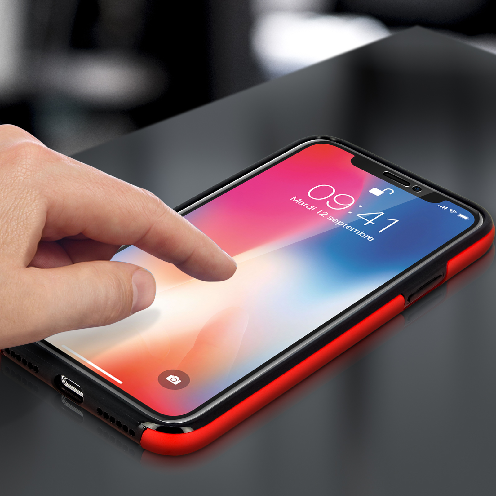 Mano che tocca lo schermo di un telefono con custodia rossa. Lo schermo mostra orologio e icone app.