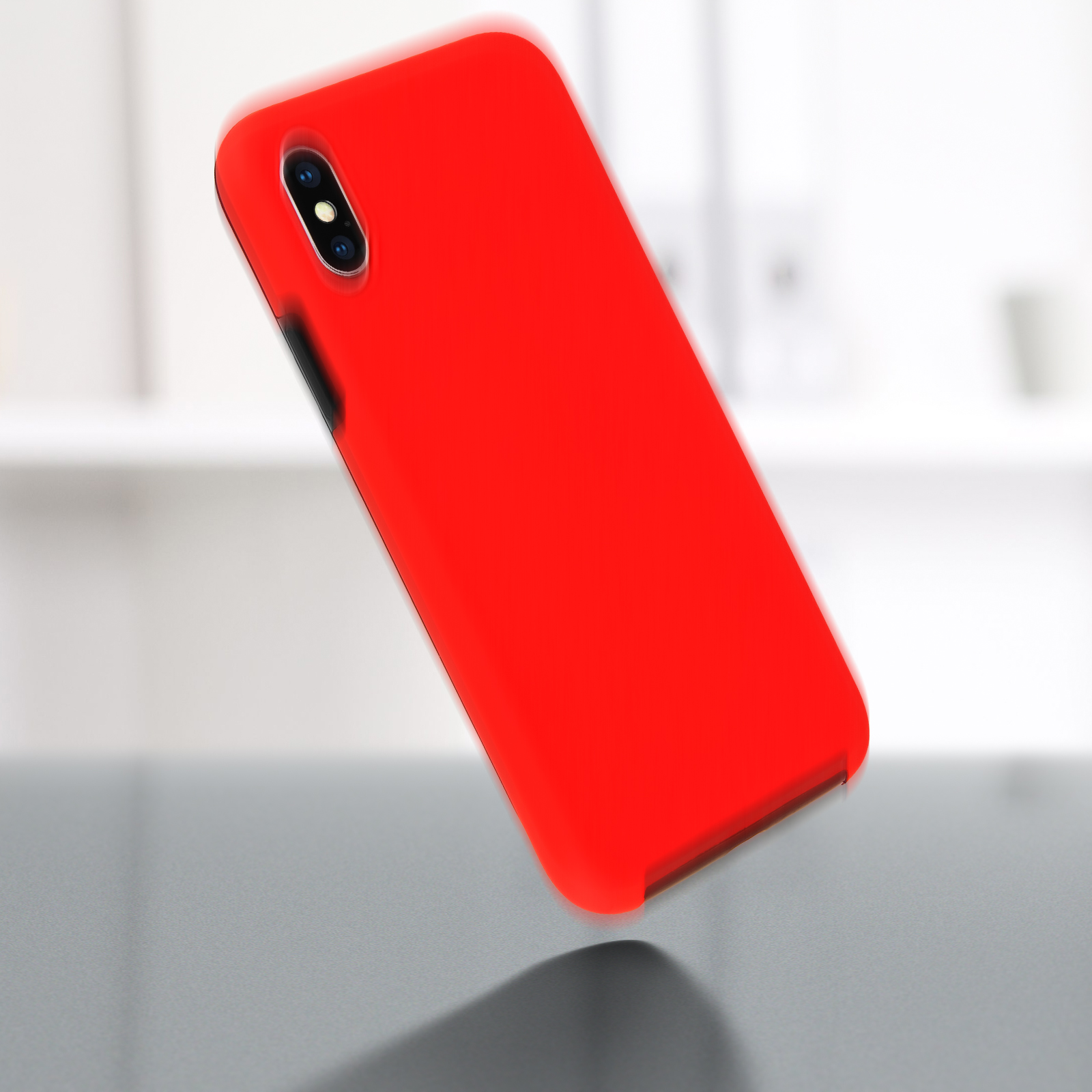 Custodia per telefono rossa che cade, con una superficie grigia. La custodia è rossa e la superficie grigia.