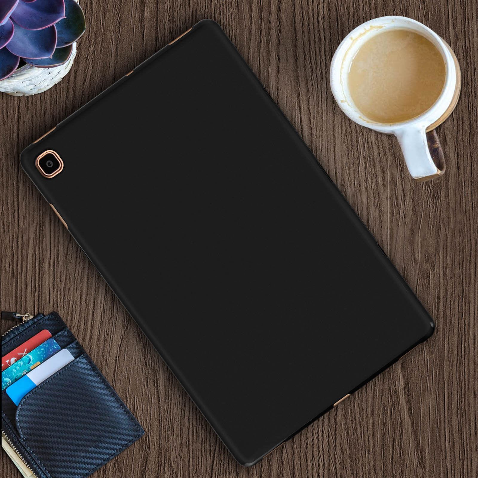 Schwarze Tablet-Hülle auf einem Holztisch, in der Nähe einer Kaffeetasse, einer Brieftasche und einer Pflanze.