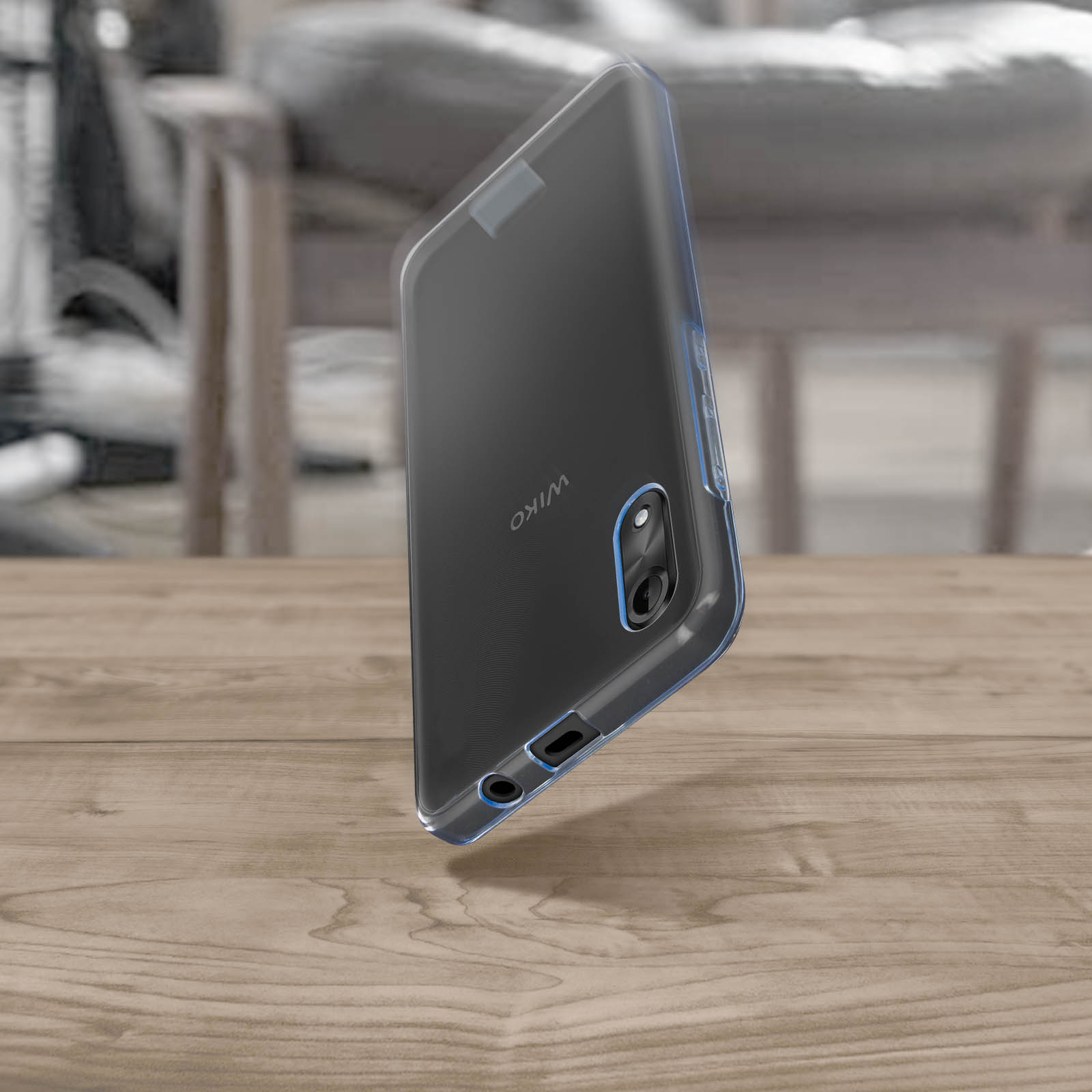 Una custodia trasparente per telefono attorno a un telefono Wiko su un tavolo di legno, con sfondo sfocato.