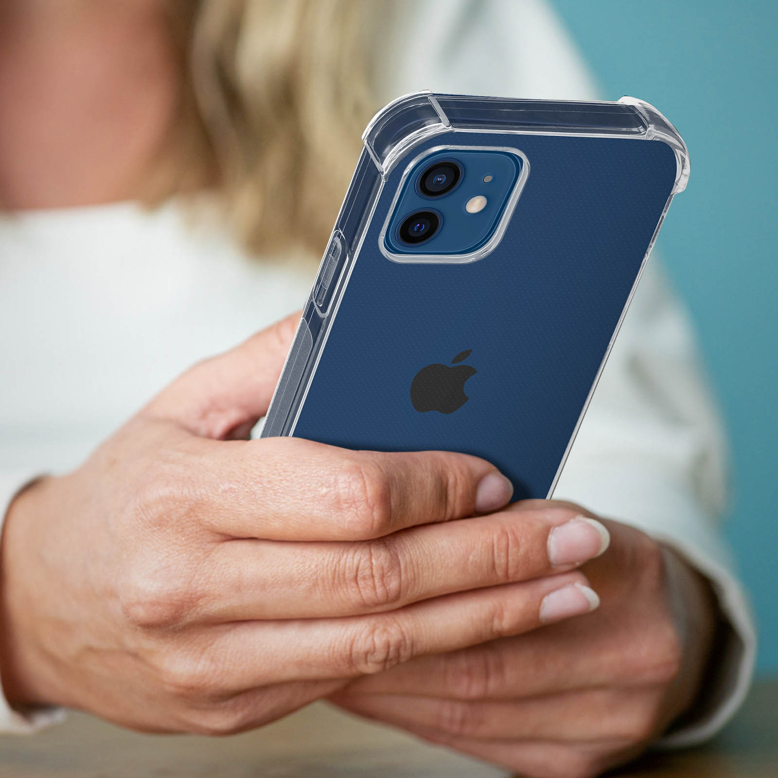 Una persona che tiene un telefono in una custodia trasparente. Il telefono è blu. Sfondo azzurro.