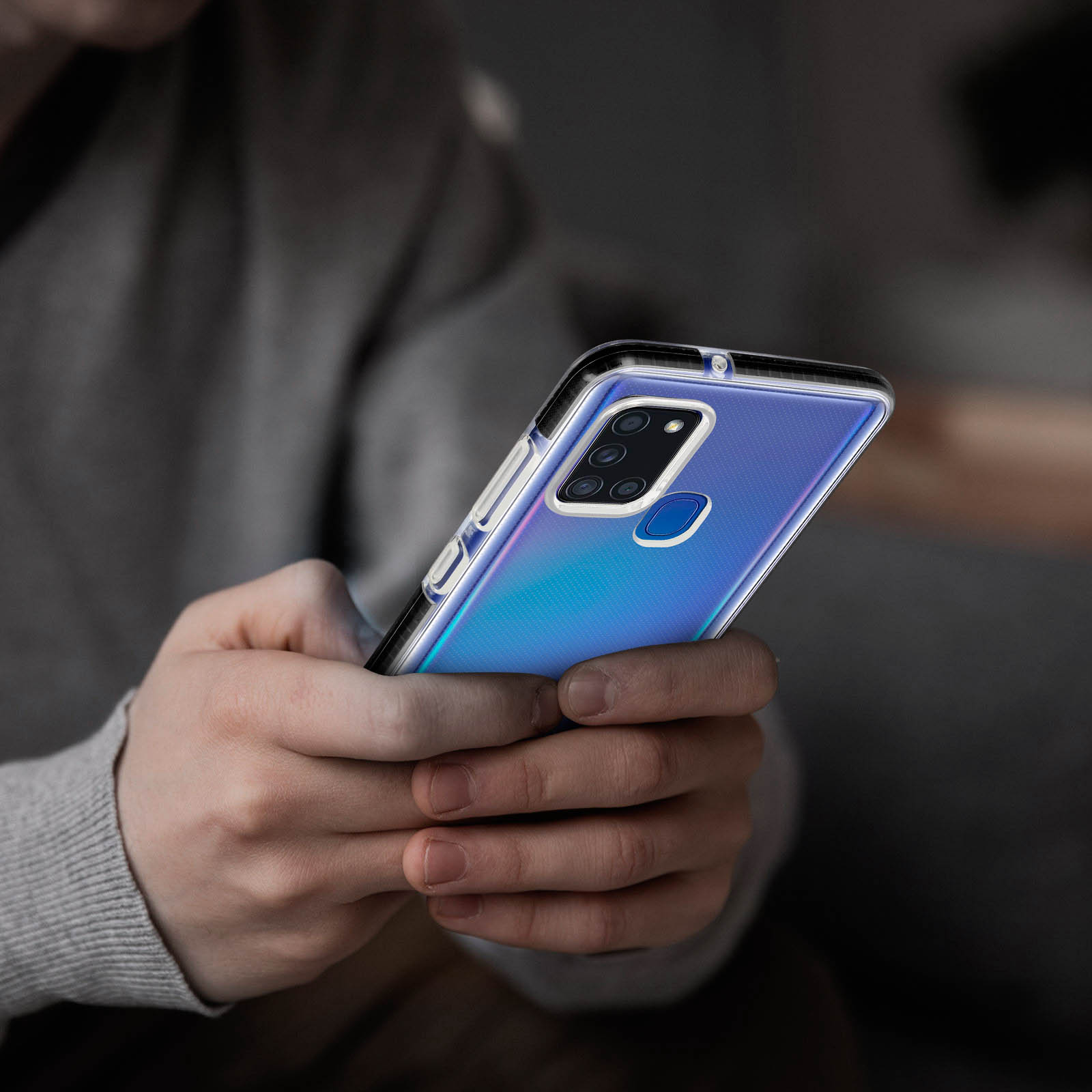Eine Person hält ein Telefon mit transparenter Hülle. Das Telefon hat eine blaue, glänzende Rückseite.