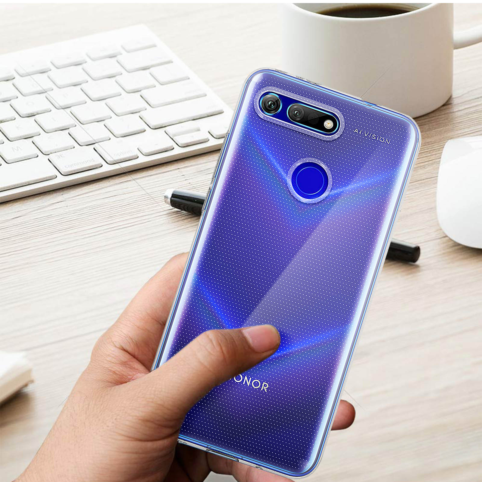 Una mano tiene una custodia blu a pois. Tastiera, tazza e penna sullo sfondo.