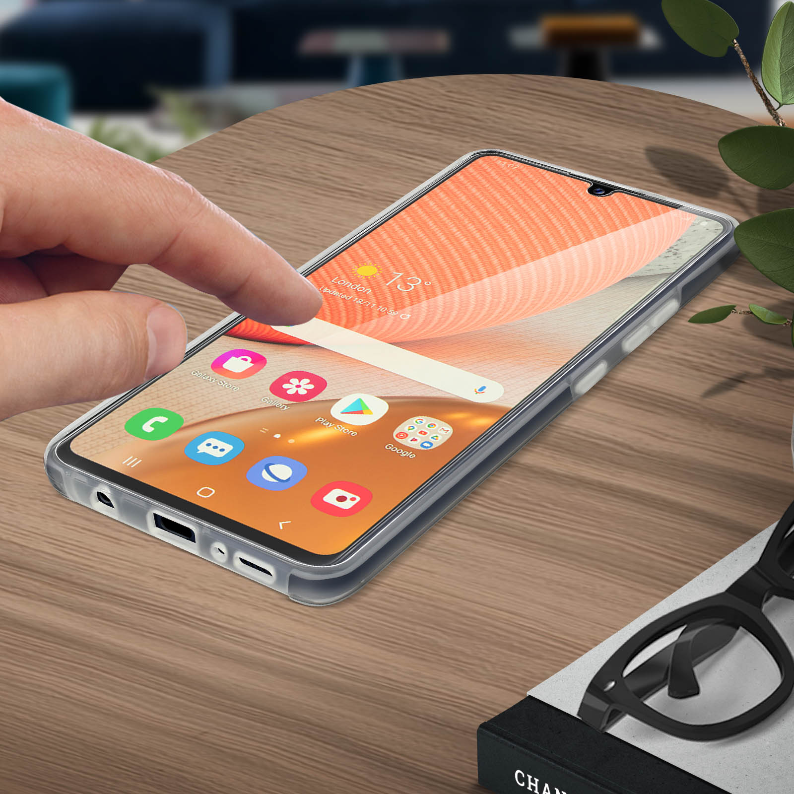 Dito che tocca lo schermo del telefono con icone delle app. Sfondo sfocato con foglie e occhiali.