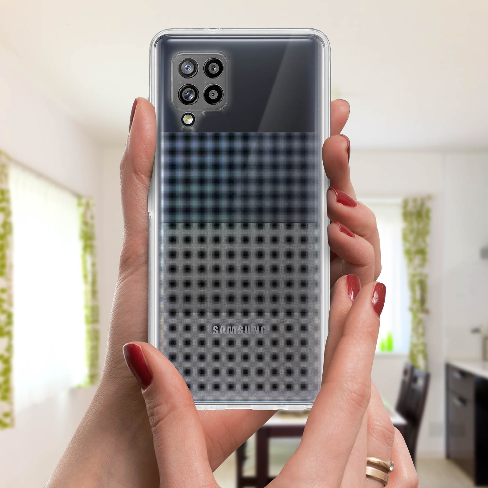 Mani che tengono un telefono con custodia trasparente, mostrando il logo Samsung. Lo sfondo è un soggiorno.
