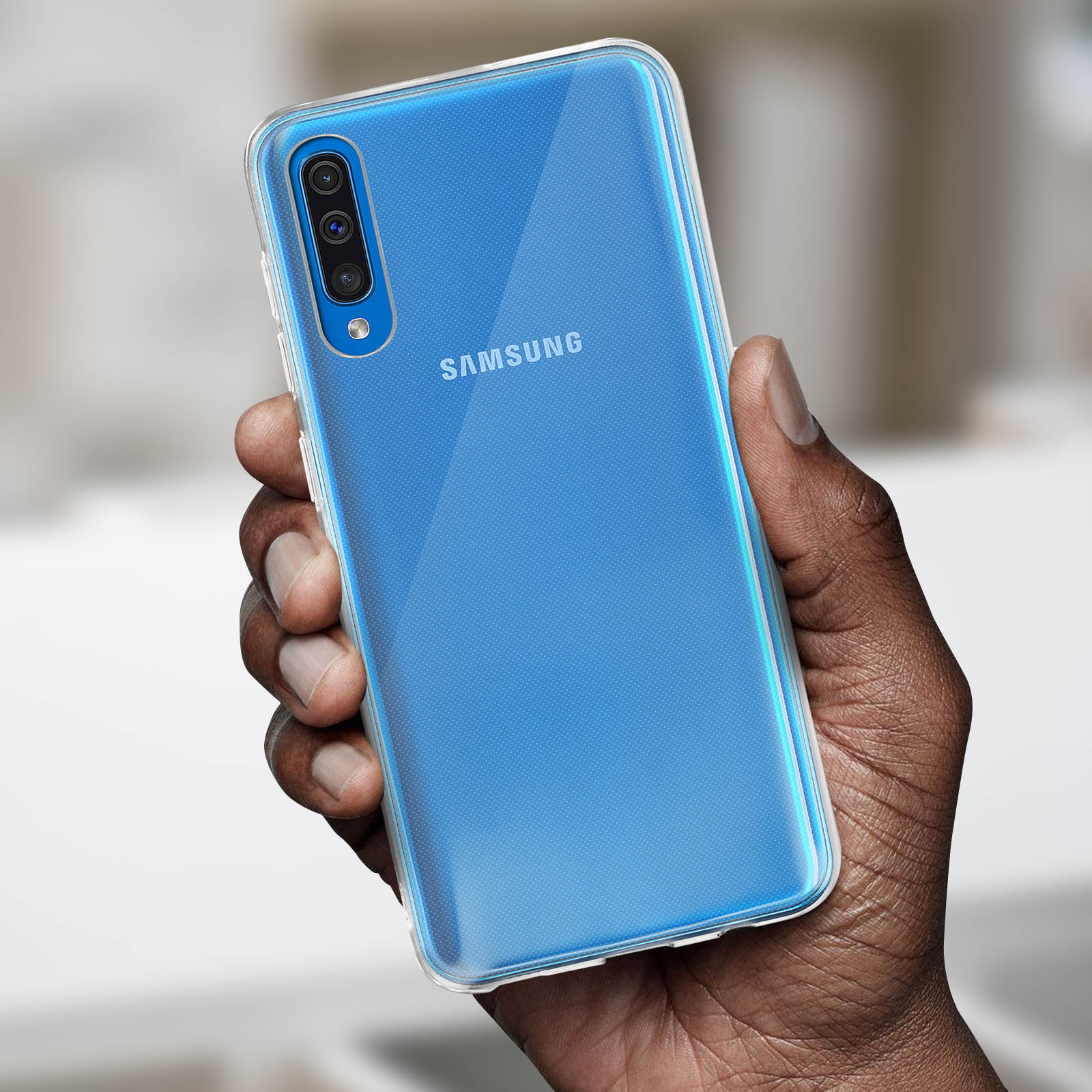 Mano che tiene un telefono Samsung in una custodia trasparente. Il telefono è blu, il retro è visibile.