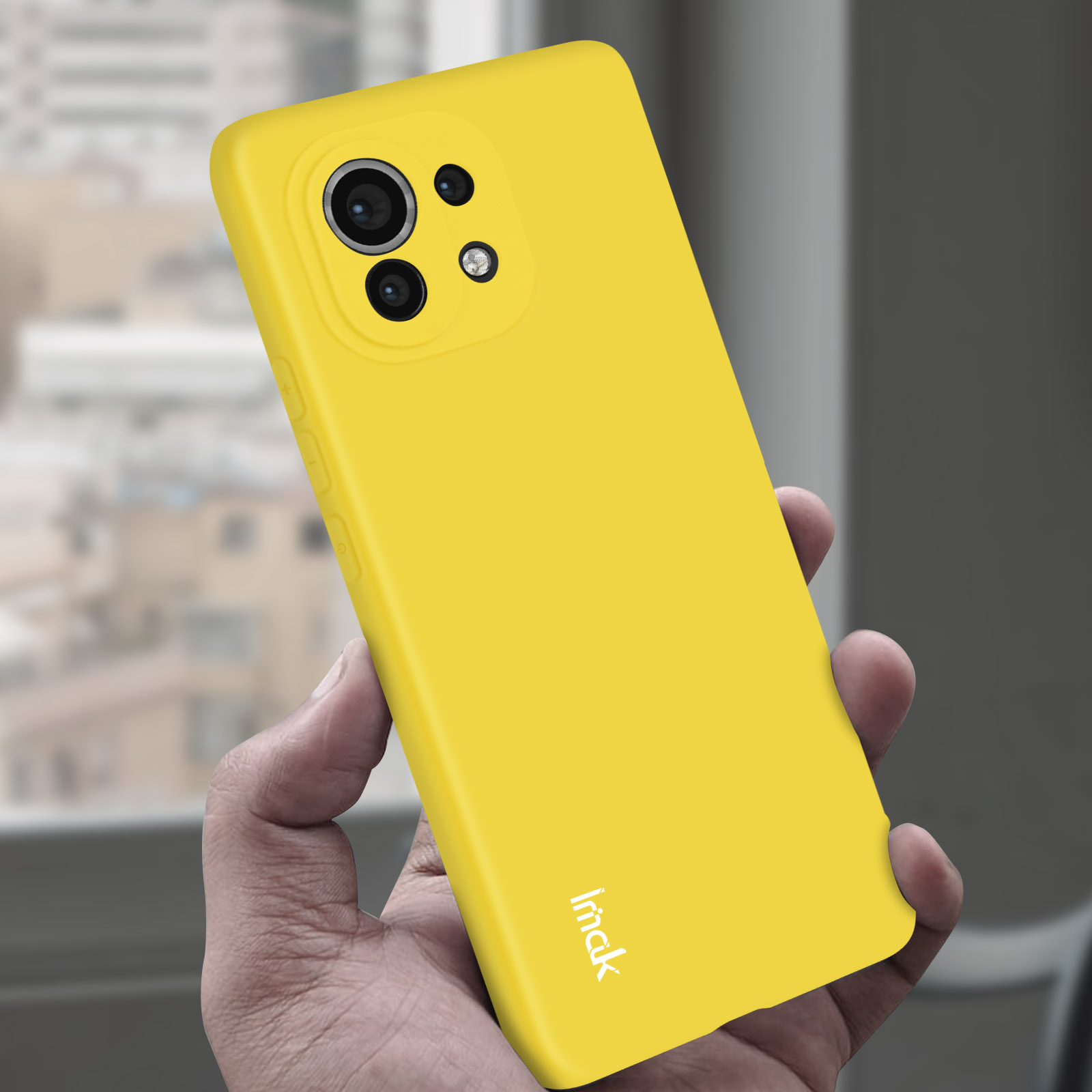 Custodia per telefono gialla su una mano con fotocamera. Sfondo sfocato.