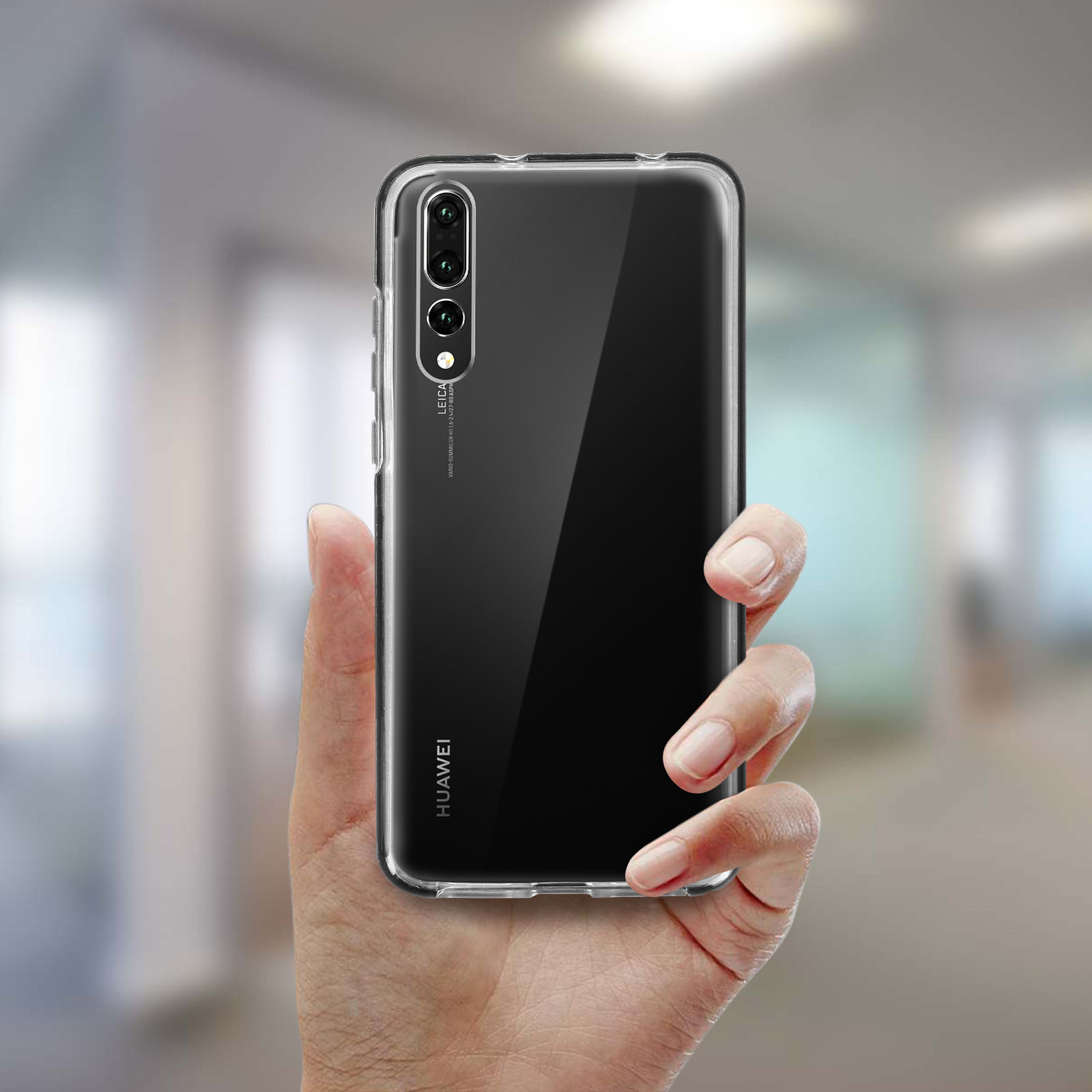 Mano che tiene una custodia trasparente per telefono su sfondo sfocato. La custodia ha il logo Huawei.