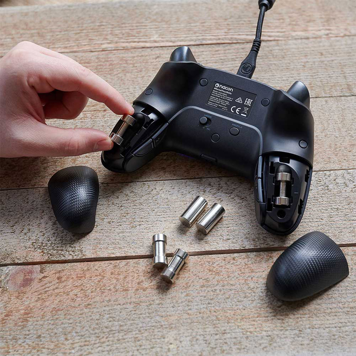 Die Hand einer Person montiert einen Gamecontroller mit zusätzlichen Komponenten auf Holz.