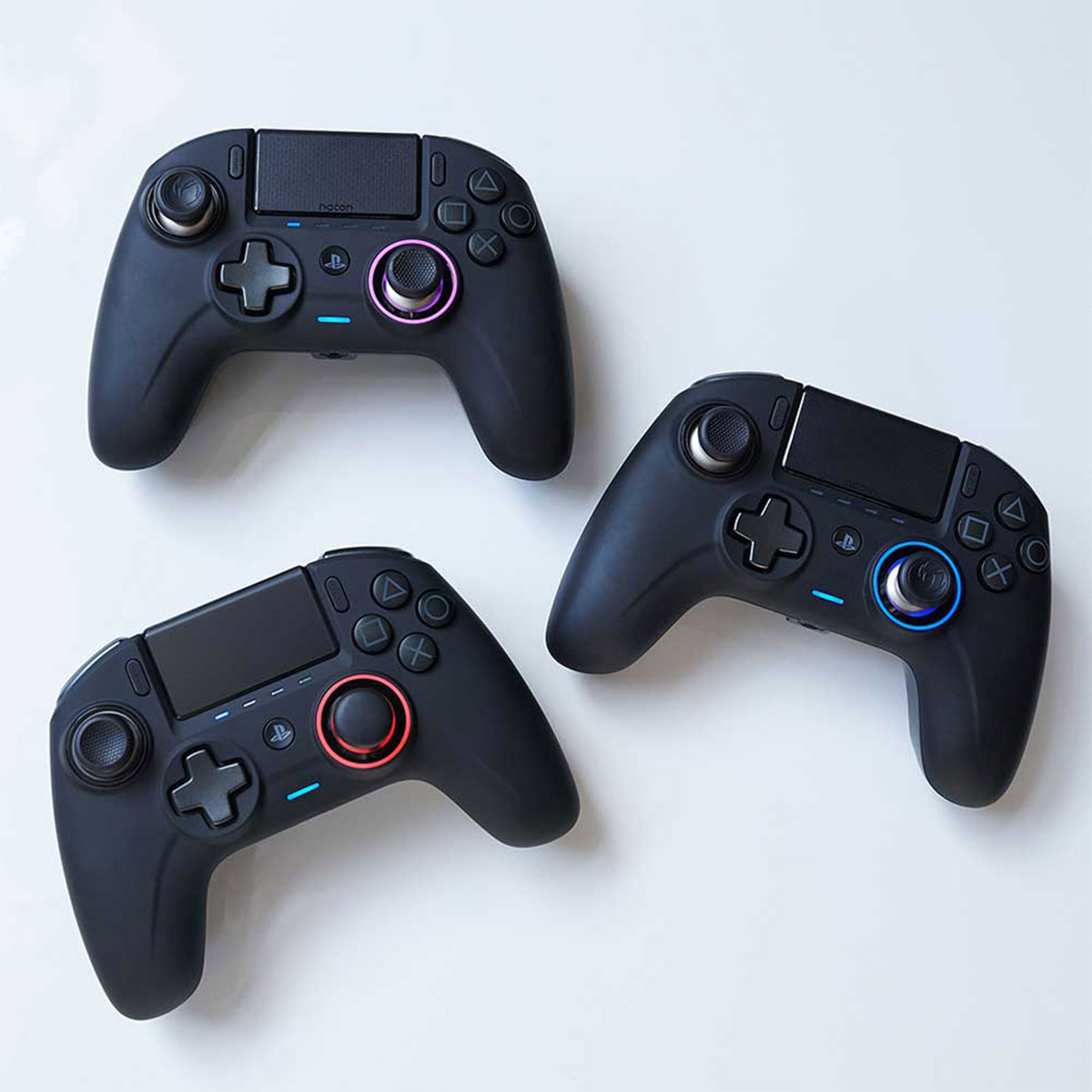 Drei schwarze Gamecontroller. Jeder hat Knöpfe. Zwei haben lila/blaue Lichter.