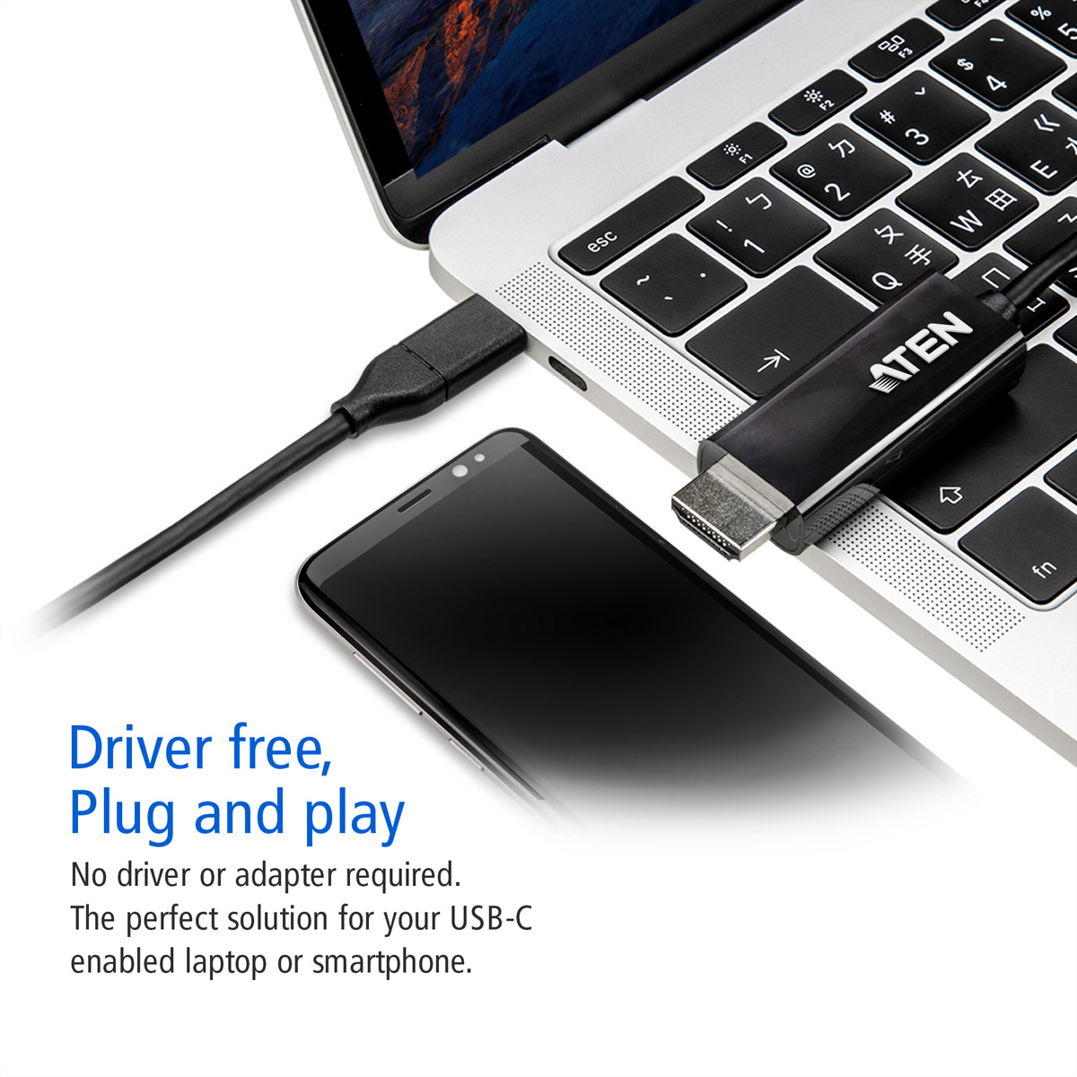 Un adaptateur USB-C vers HDMI noir est branché sur un ordinateur portable, un téléphone est sur le bureau.