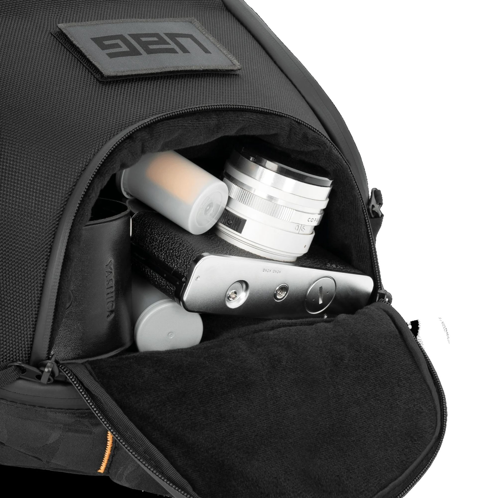 Offener Rucksack mit Kameraausrüstung: Objektiv, Filmkanister, Kamera, schwarzes Etui.