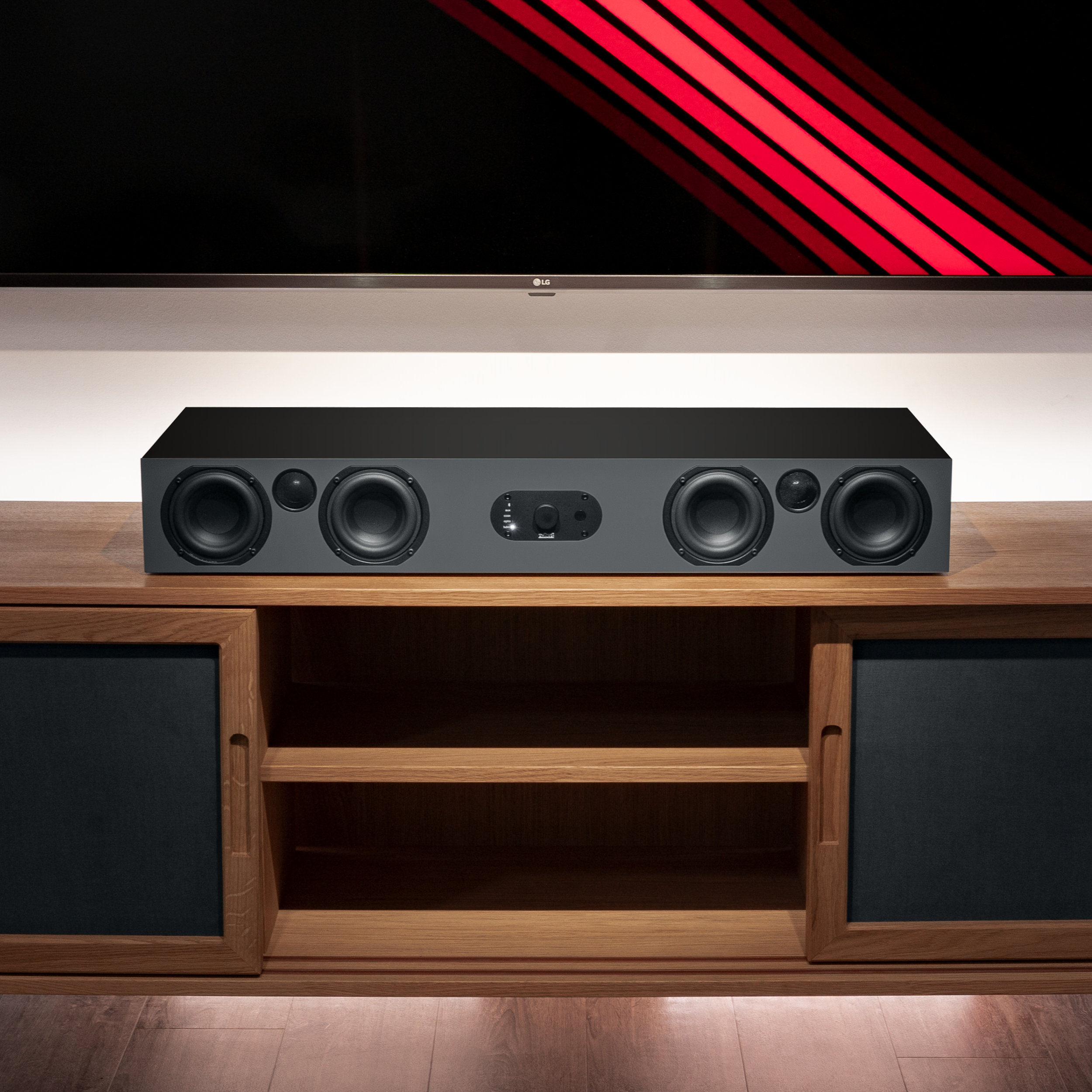 Eine schwarze Soundbar auf einem Holzschrank, mit einem großen schwarzen Fernsehbildschirm und roten Lichtern im Hintergrund.