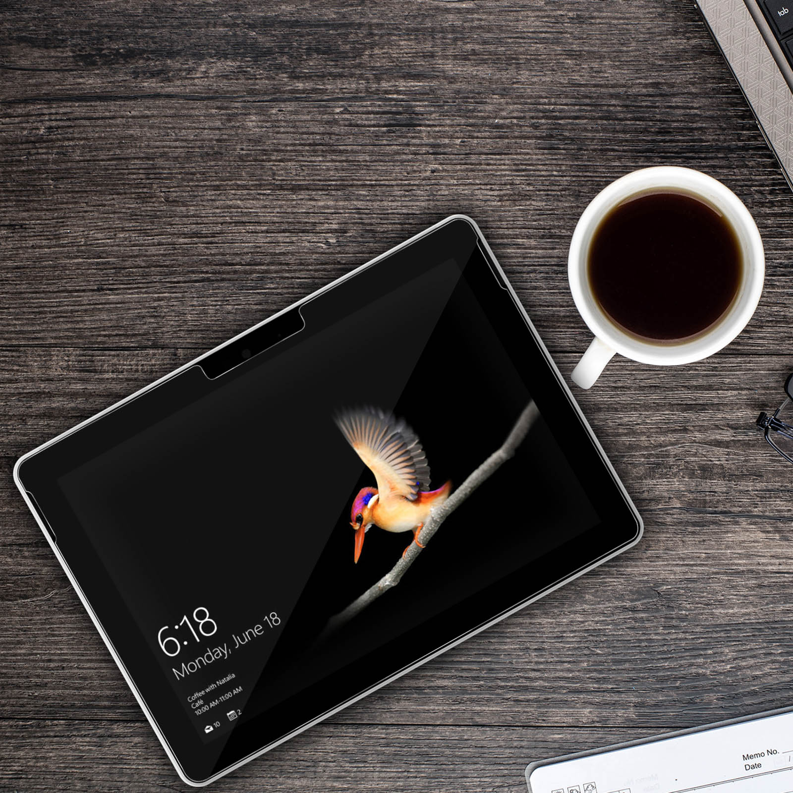 Tablet su legno, con immagine di uccello sullo schermo e tazza di caffè.