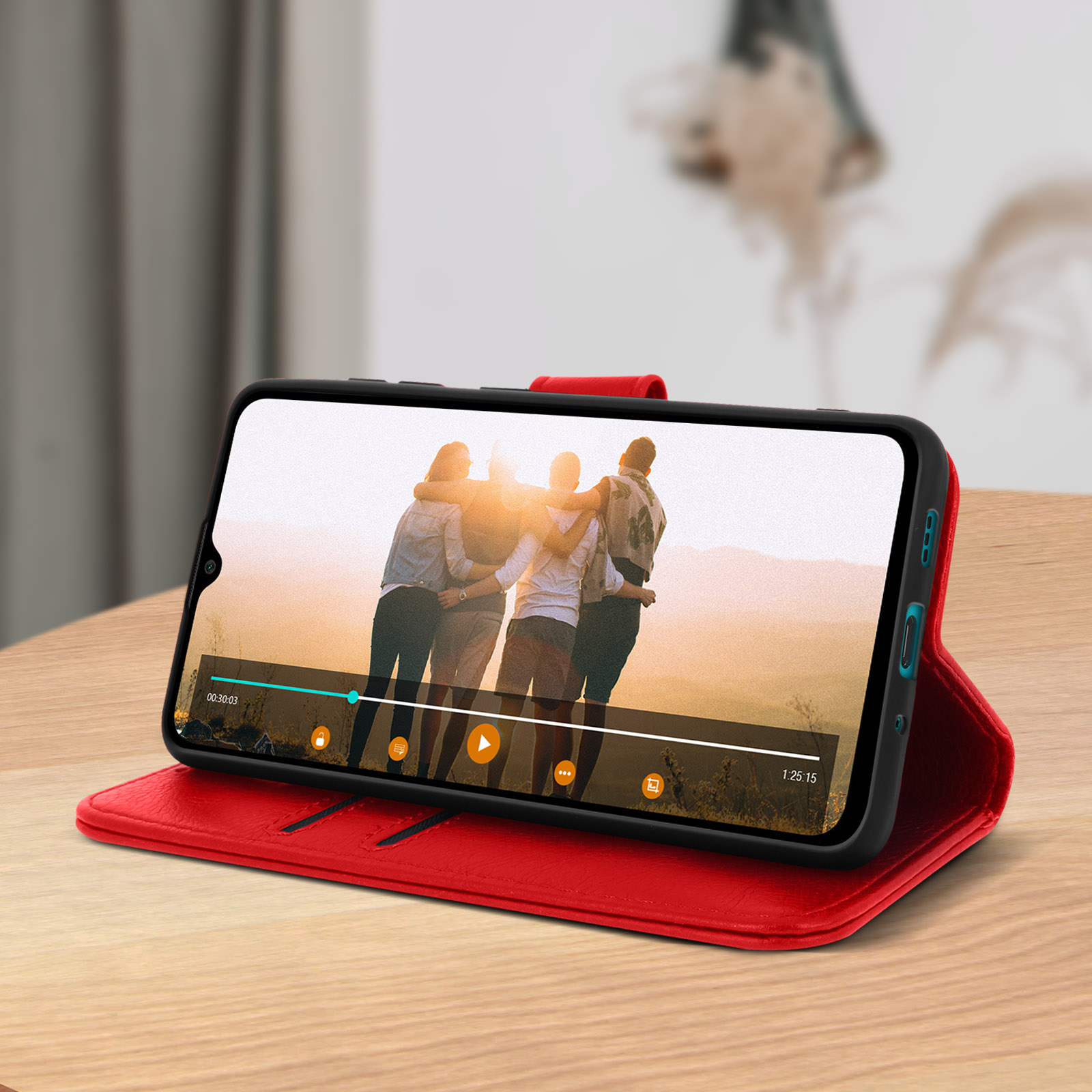 Téléphone dans un étui rouge, montrant une vidéo à l'écran. Des personnes sont visibles.