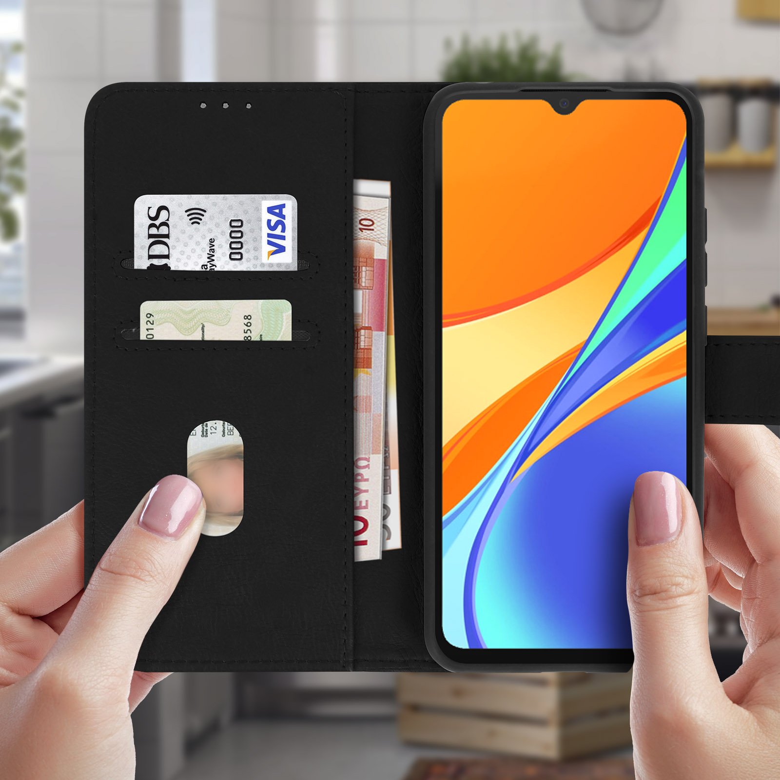 Een zwarte telefoonhoes portemonnee open met telefoon, kaarten en geld erin. Handen houden het vast.