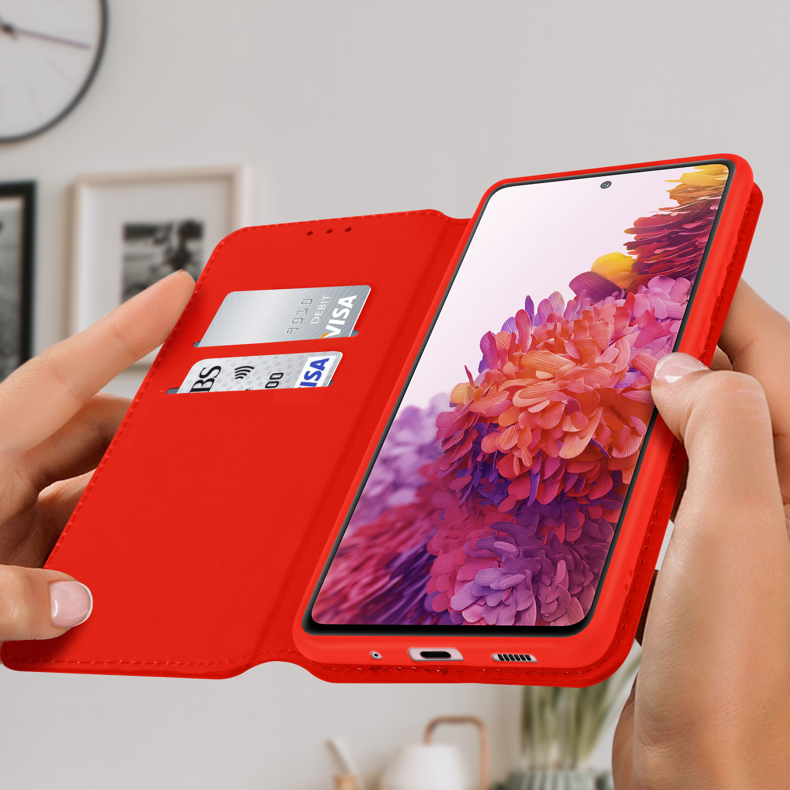 Eine Person hält eine rote Handyhülle mit einem Telefon darin. Eine Kreditkarte ist in einem Schlitz sichtbar.