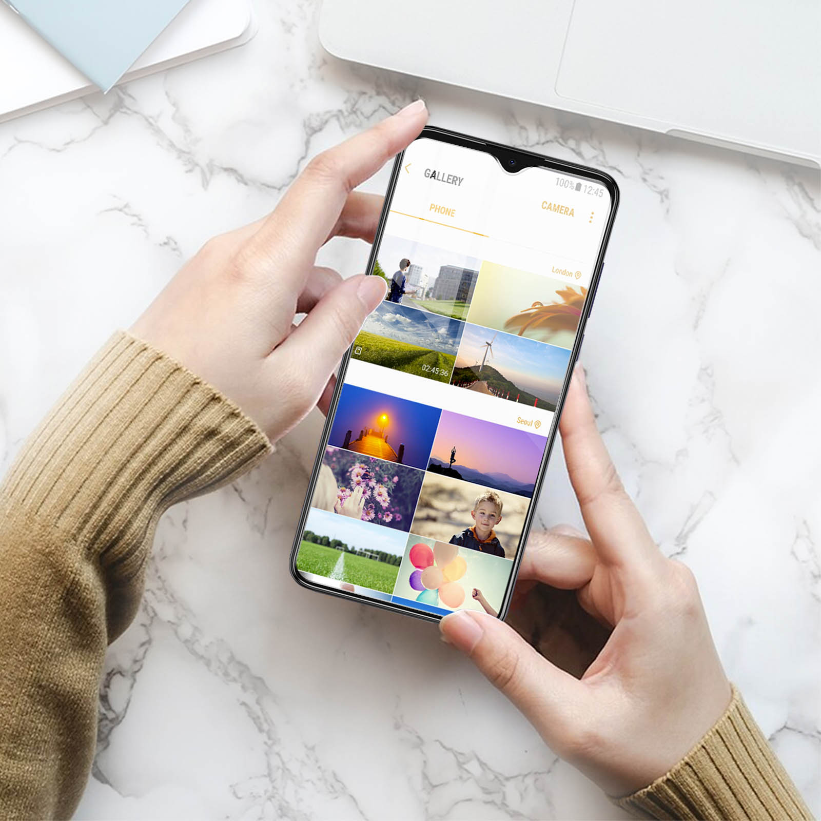 Una persona che tiene in mano un telefono che mostra foto. Il telefono è su una superficie di marmo.