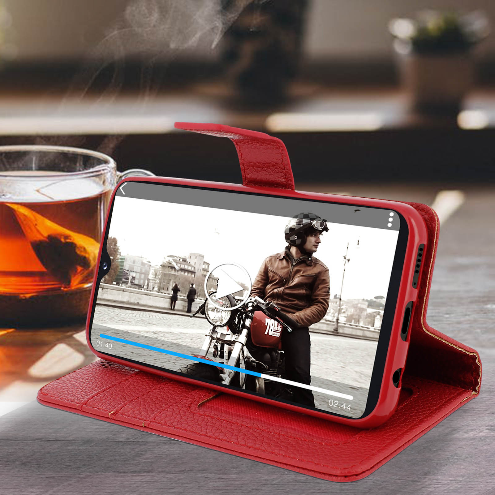Rode telefoonhoes toont een video van een motorrijder op een rode motor. Een kopje thee op de achtergrond.