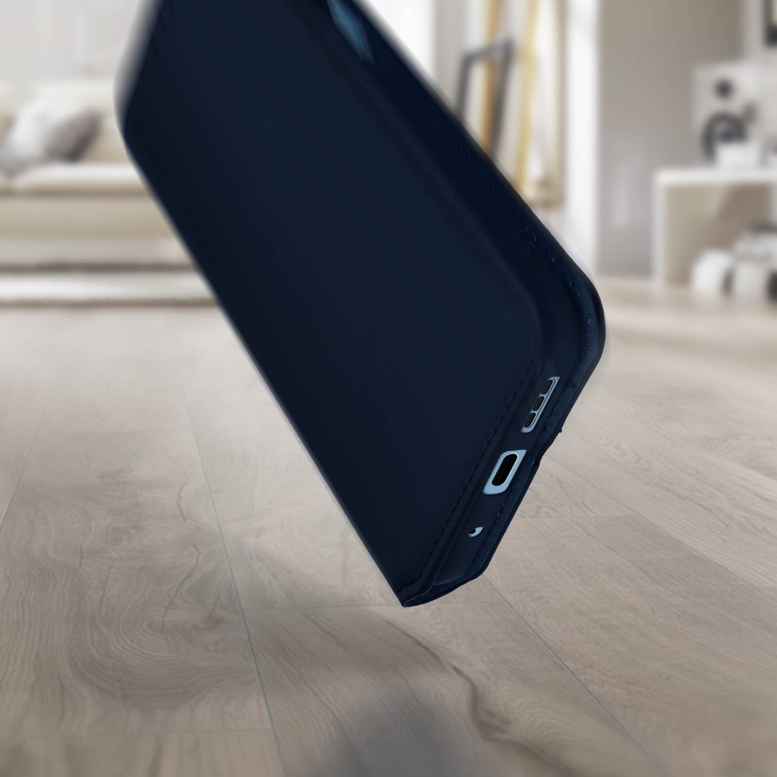 Un étui de téléphone tombant sur un plancher en bois. L'étui est bleu foncé.