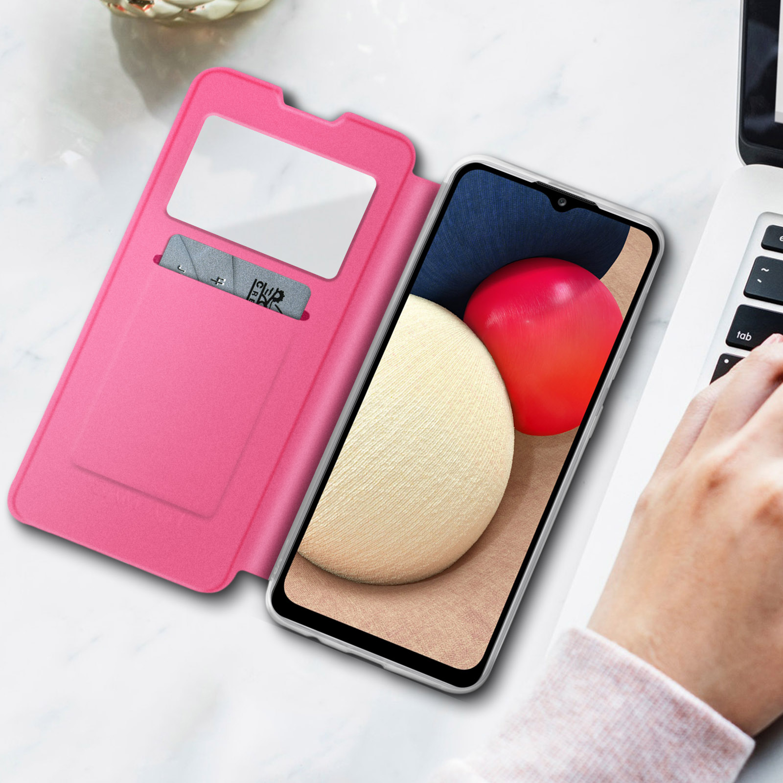 Una custodia rosa per telefono aperta per rivelare un telefono e uno slot per schede. Una mano è su un laptop.