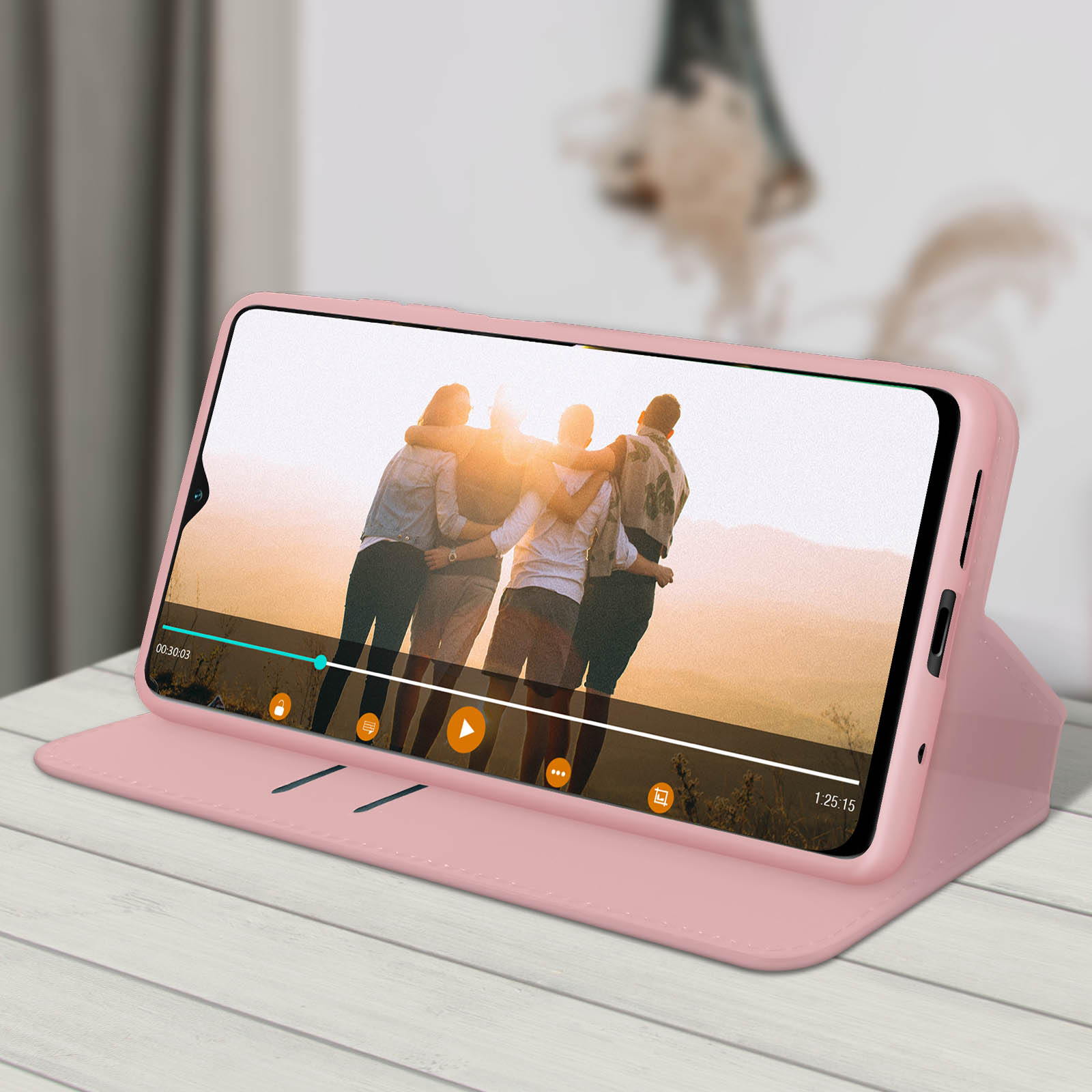 Una custodia rosa per telefono con un telefono che mostra un video di persone, su una superficie di legno.
