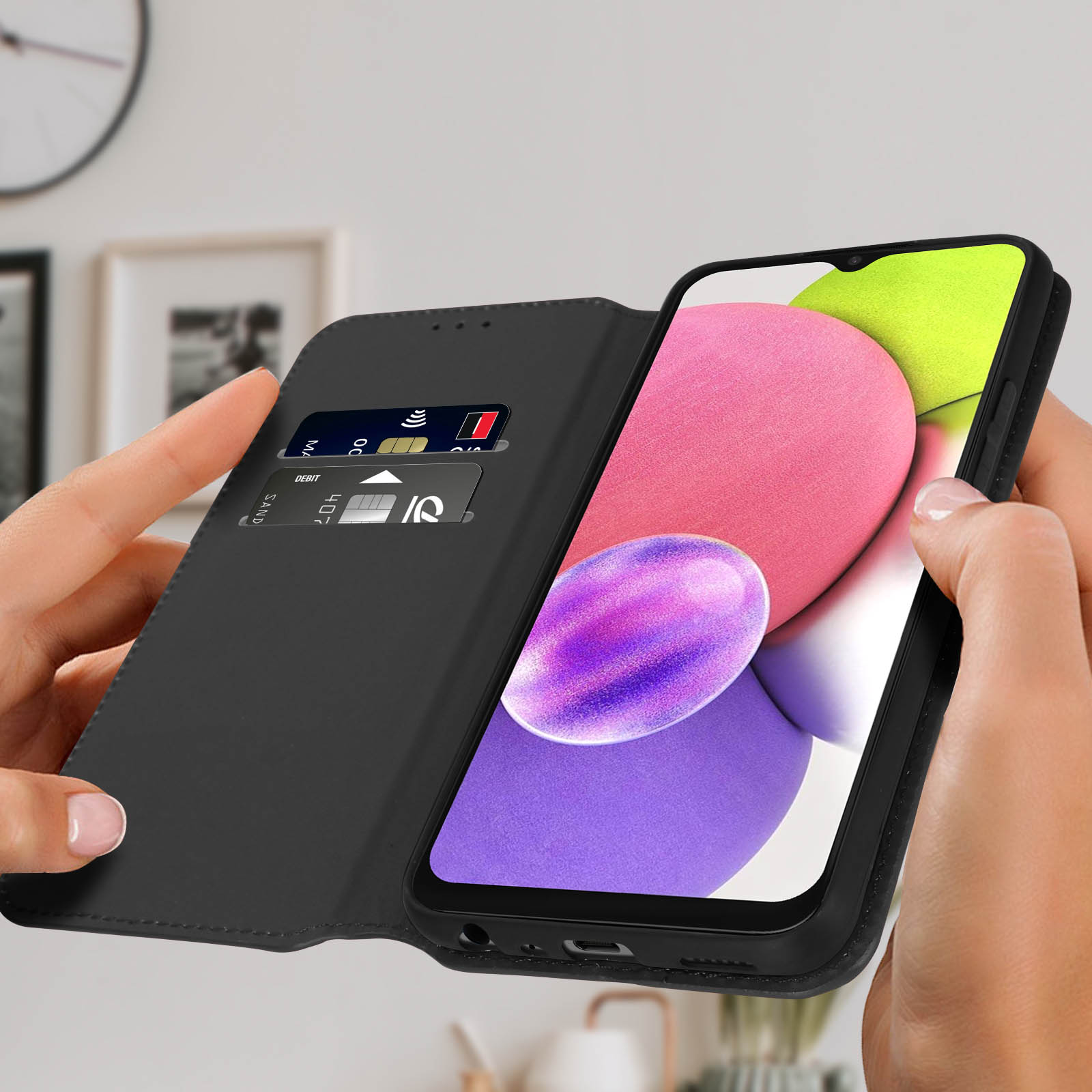 Un telefono nero in una custodia nera, tenuto in mano. Lo schermo mostra forme astratte colorate.