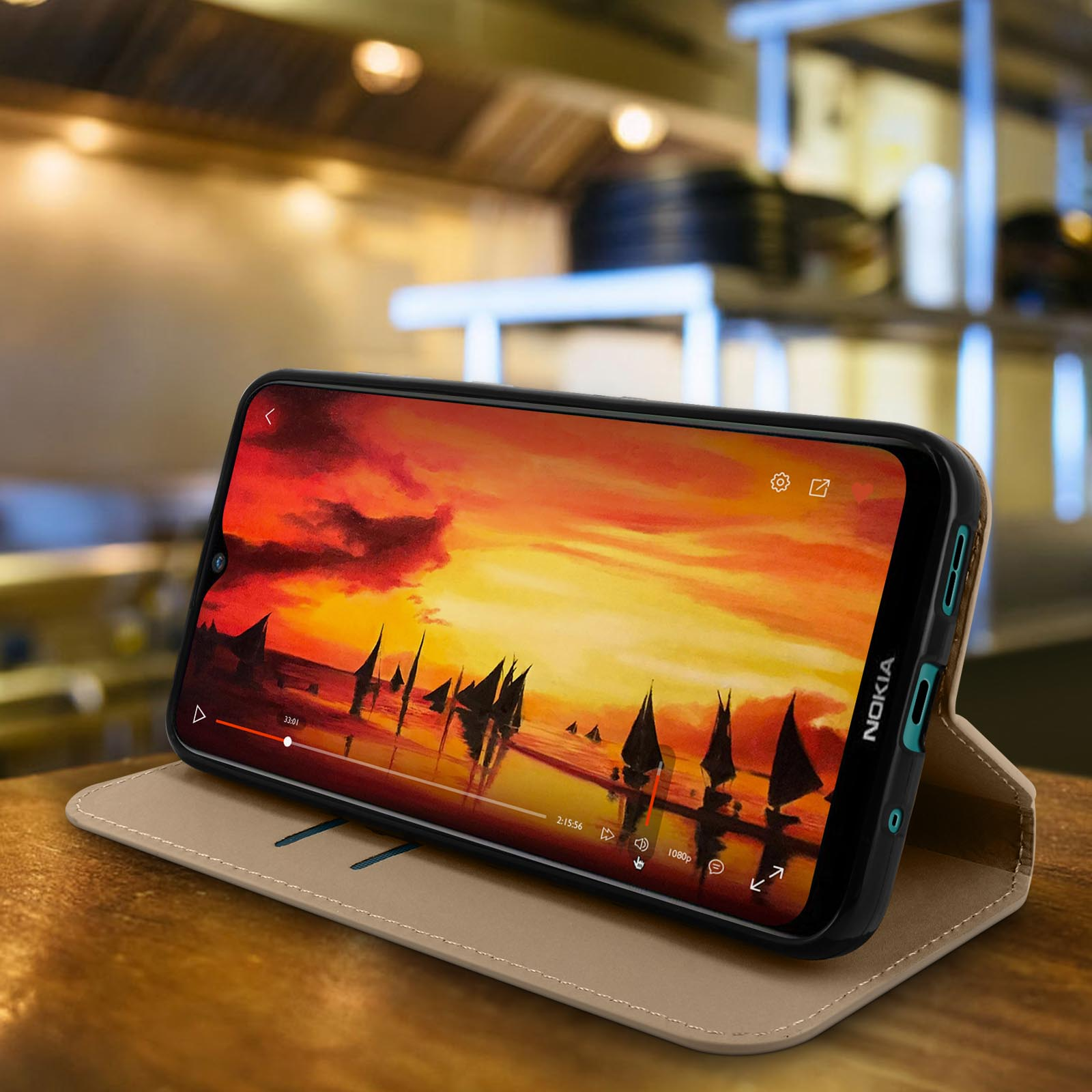 Un telefono in una custodia marrone, che mostra un video del tramonto, su un tavolo di legno.