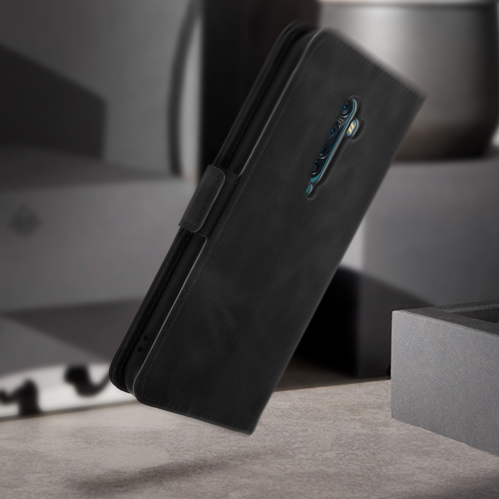 Un étui de téléphone noir est incliné. Son intérieur est visible. Le fond est gris métallique.