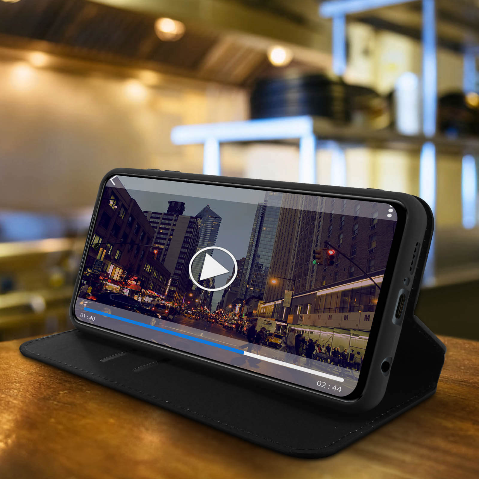 Smartphone dans un étui en mode support, diffusant une vidéo. Le téléphone est sur une surface en bois.