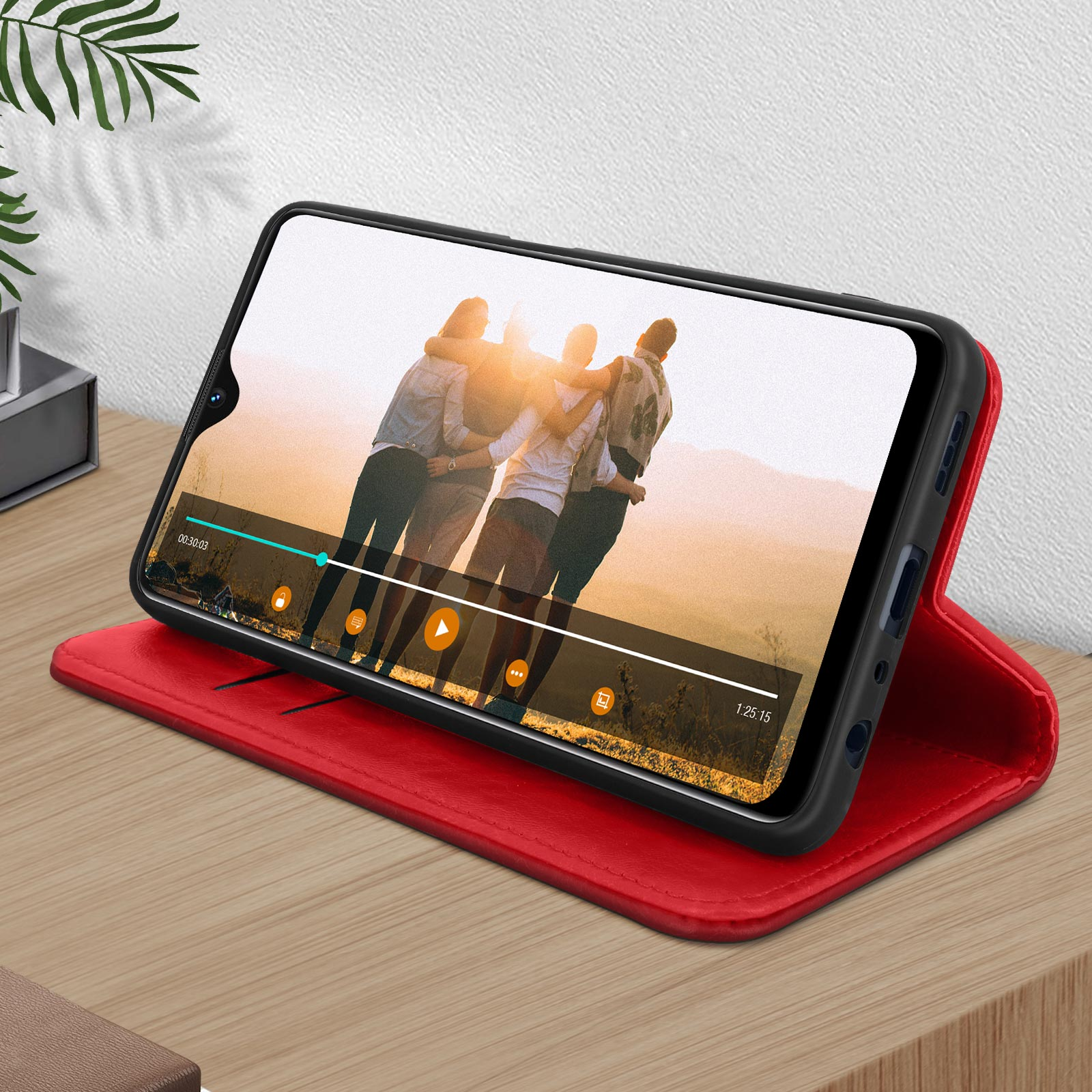 Telefoon in rode hoes toont video van mensen. Rode hoes ligt op een houten tafel.