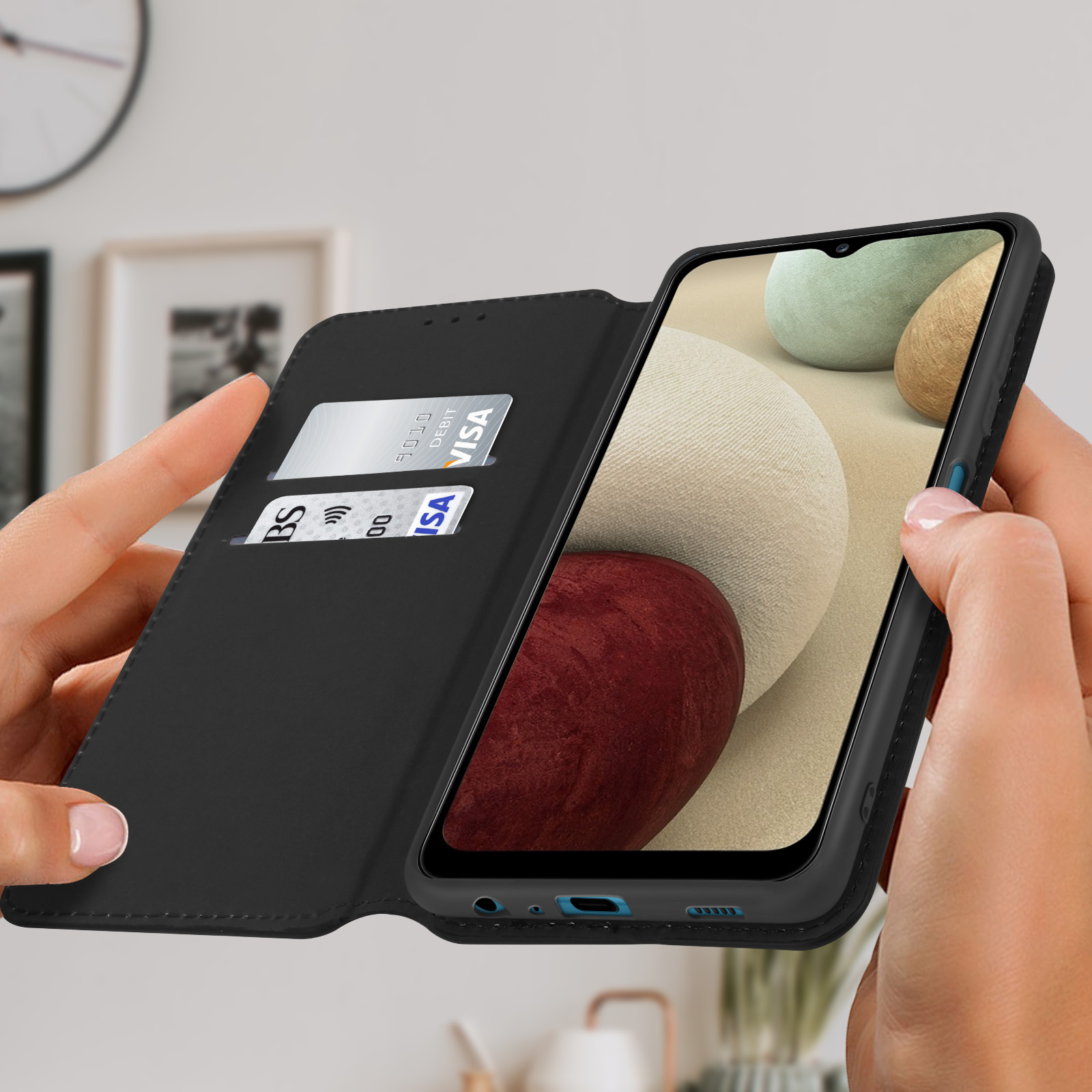 Étui portefeuille en cuir noir avec un smartphone à l'intérieur. Mains tenant le portefeuille. Cartes visibles.