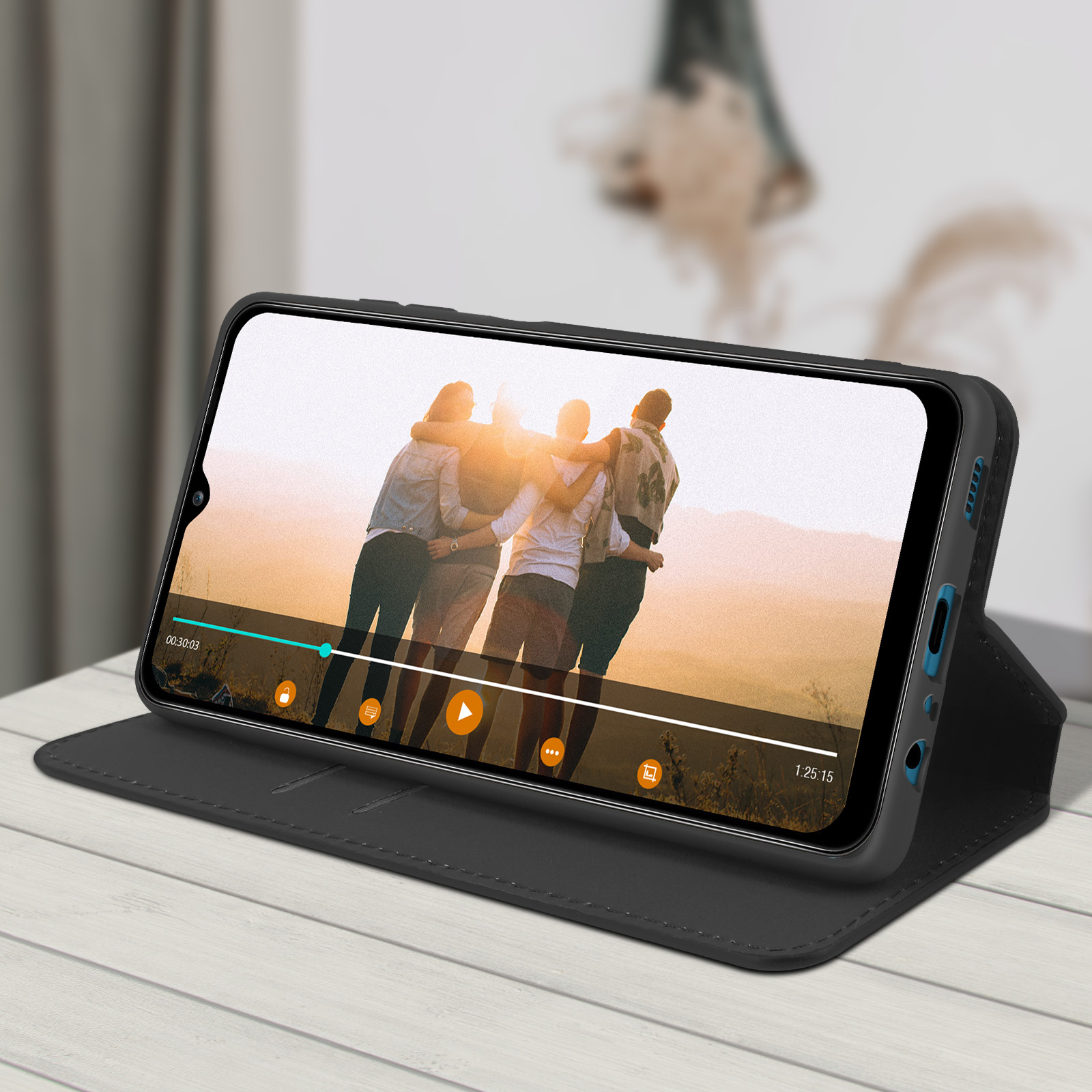 Téléphone dans étui noir sur table blanche. Affiche une vidéo avec un groupe.