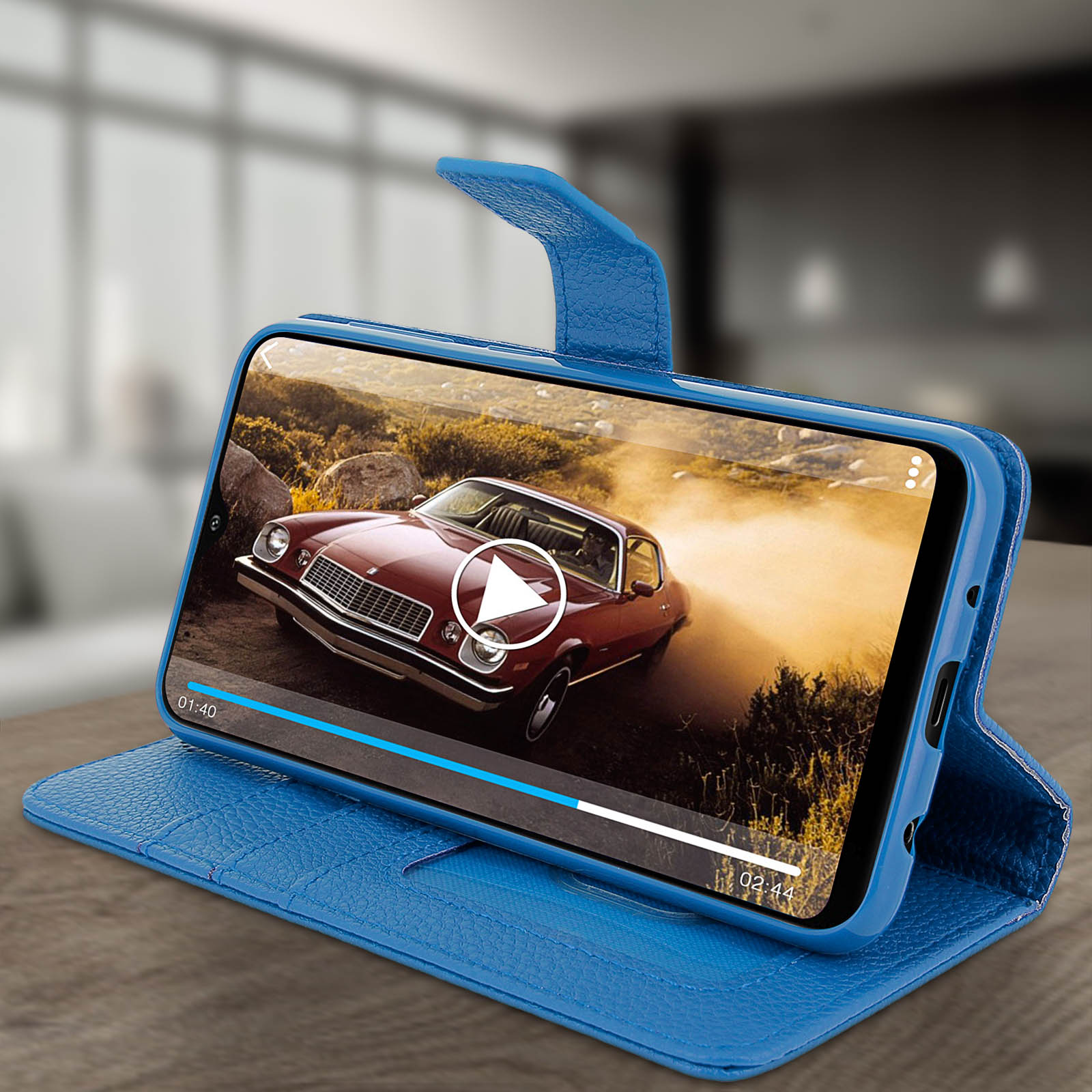 Een telefoon in een blauwe hoes, met een autovideo op een tafel in een kamer.