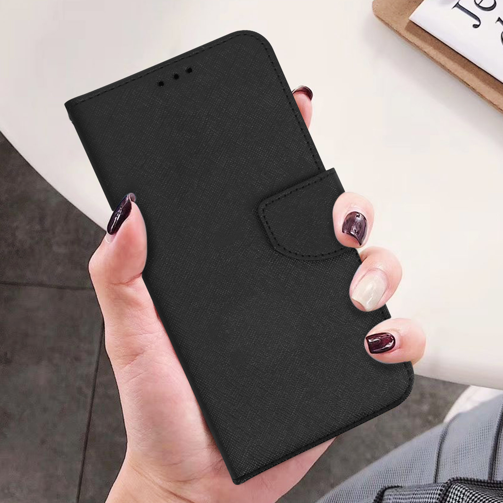 Una mano che tiene una custodia per telefono nera. La custodia è chiusa e ha una chiusura magnetica.