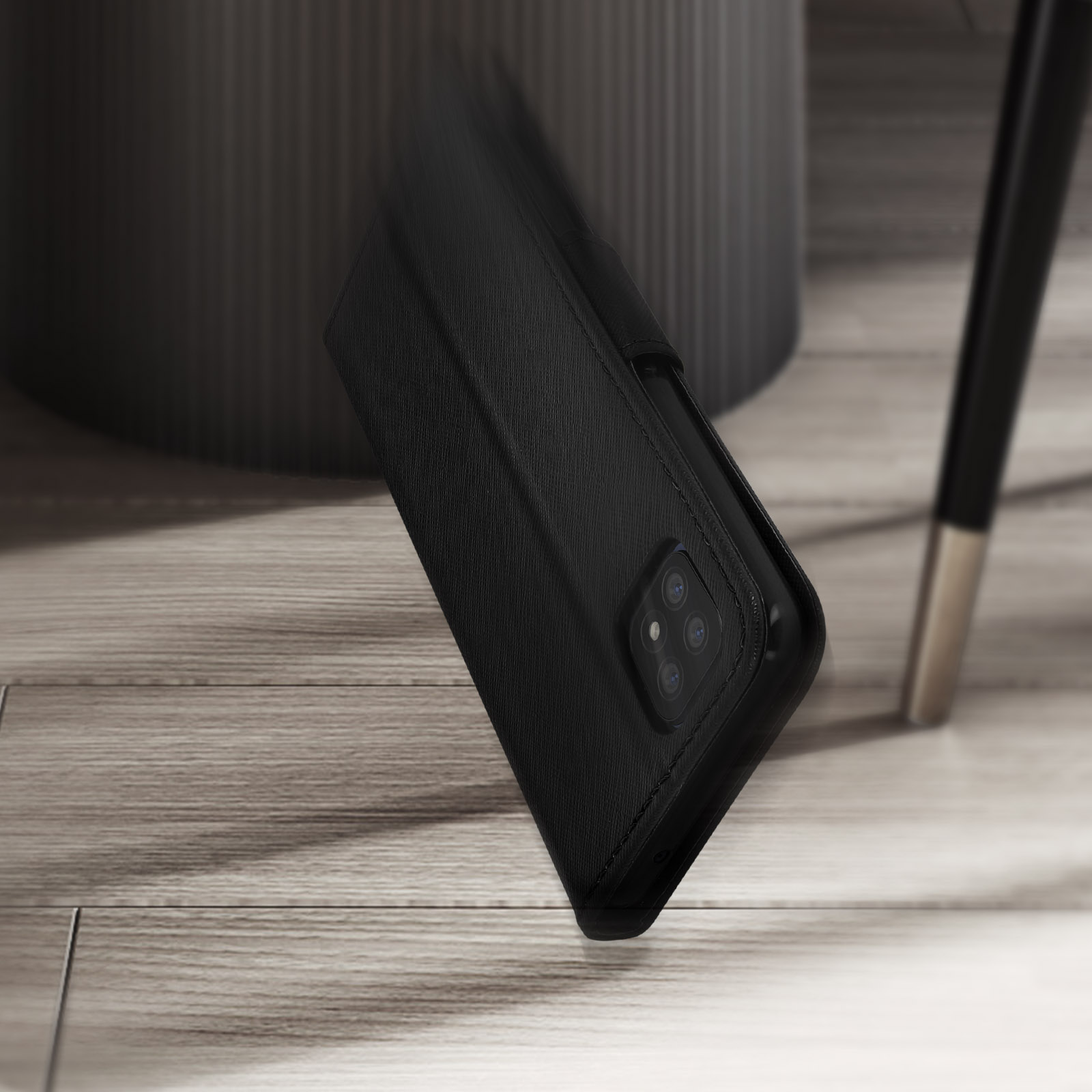 Custodia nera per telefono su tavolo. Sfondo sfocato. Gamba della sedia nera visibile.