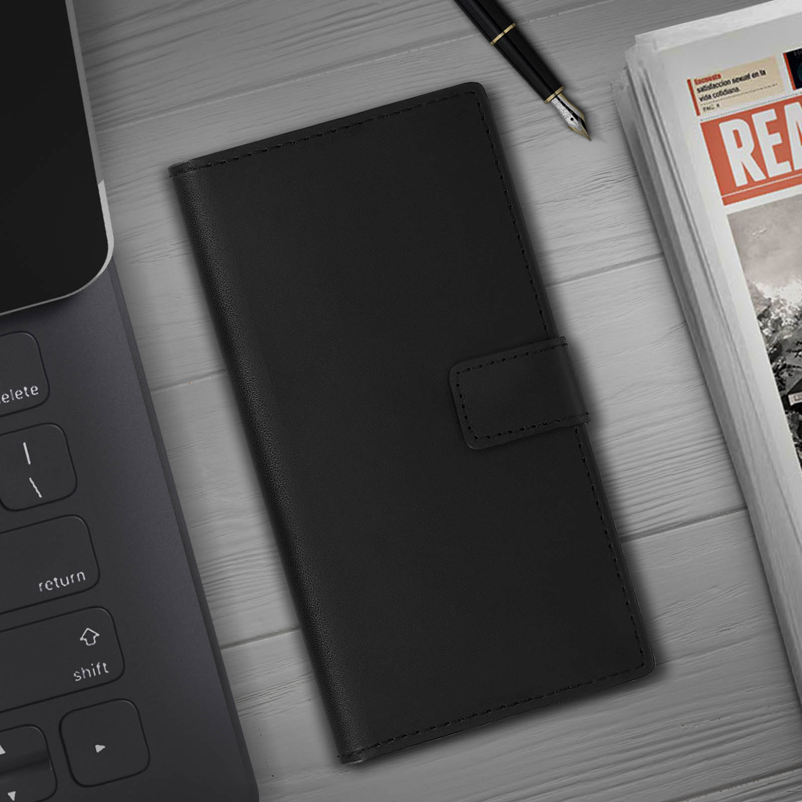 Étui de téléphone noir sur une surface en bois, avec un ordinateur portable et journal en arrière-plan.