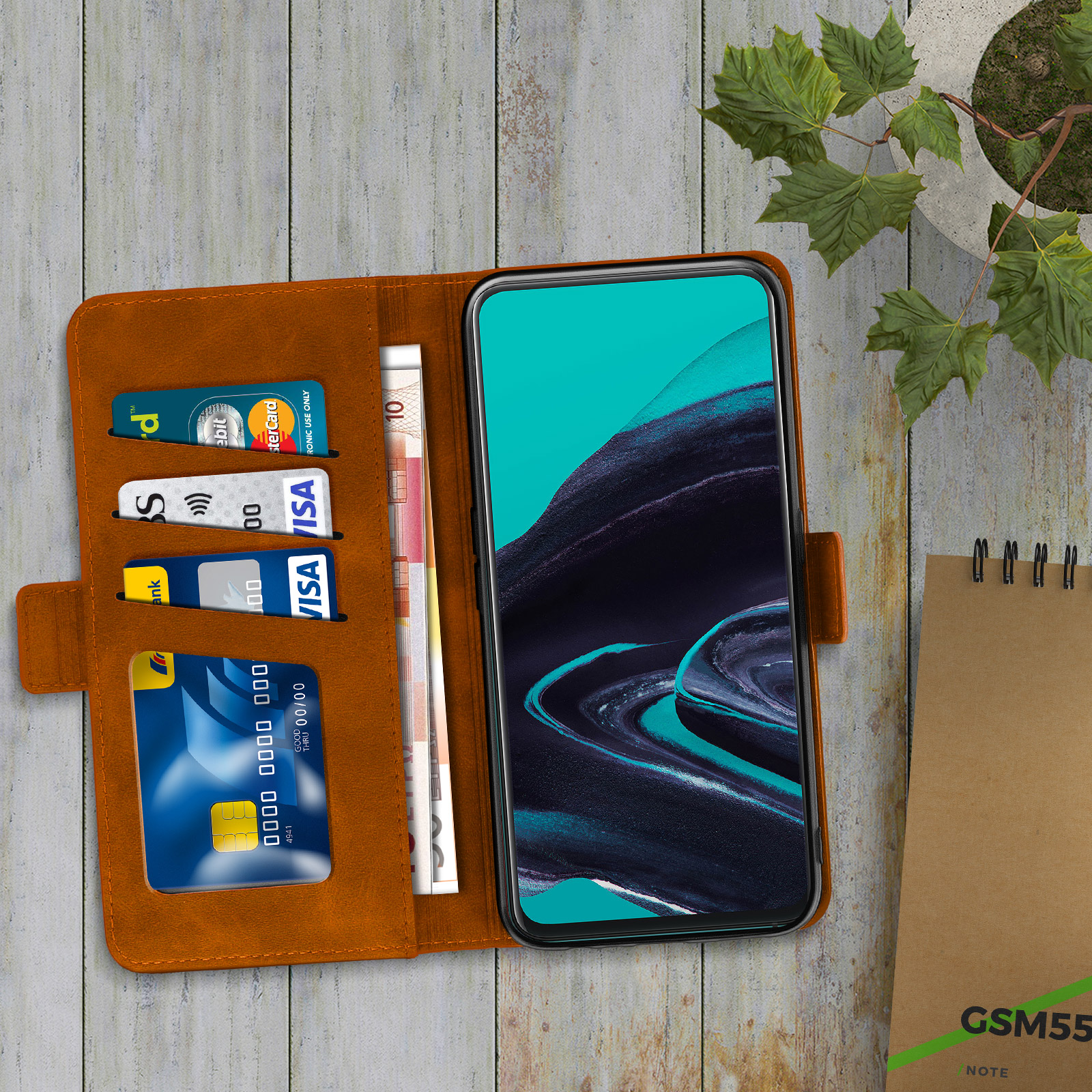 Un téléphone dans un étui portefeuille marron avec cartes de crédit et espèces, sur une table en bois.