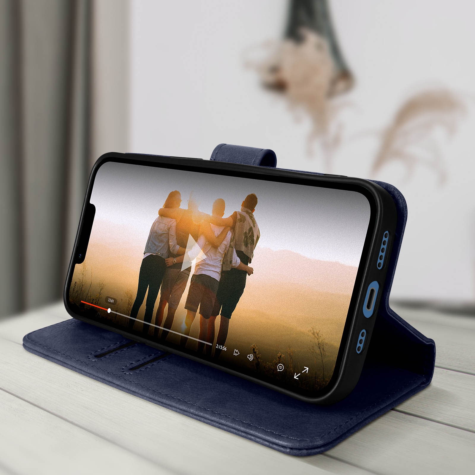 Un telefono in una custodia blu è aperto e mostra un video. La custodia è su un tavolo.