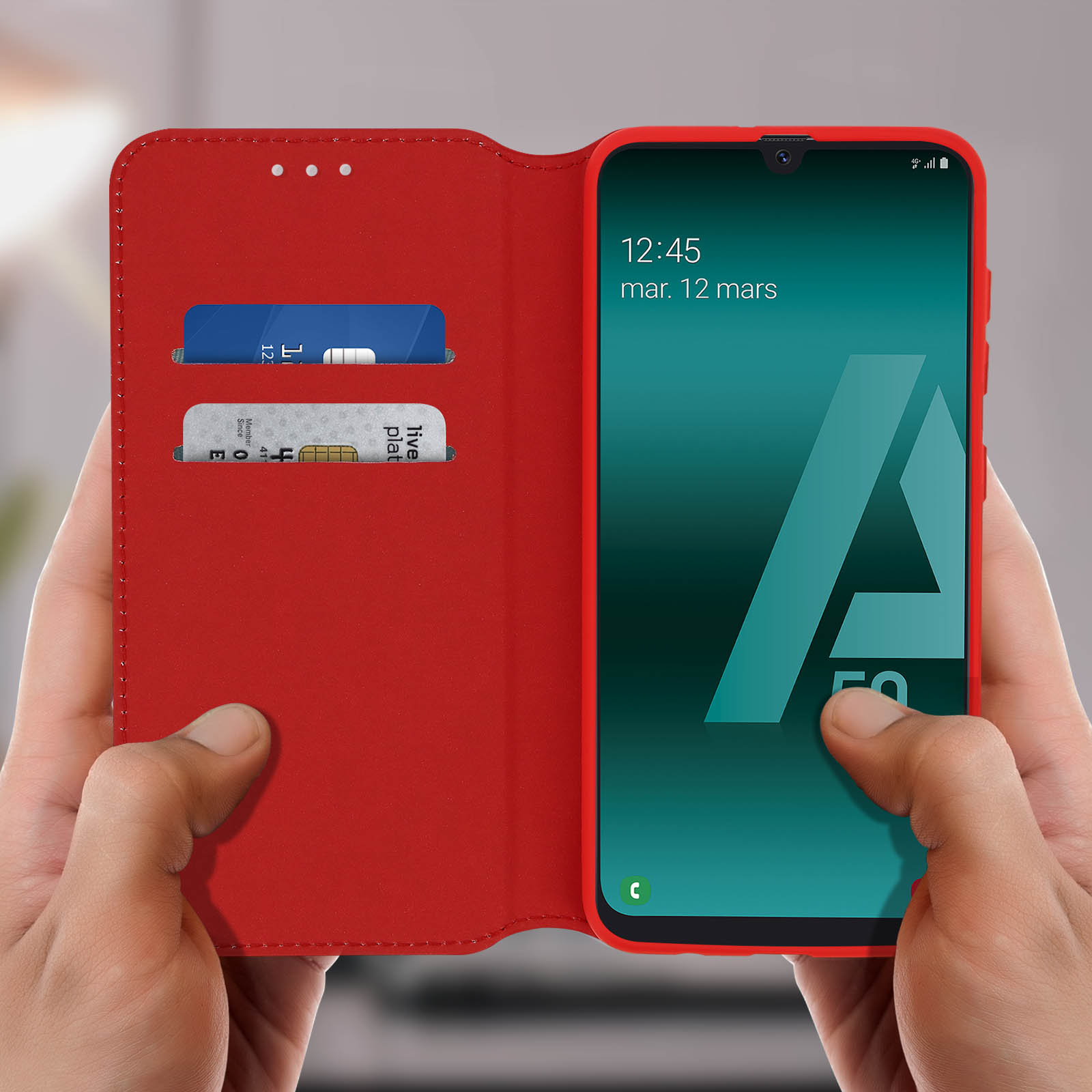 Custodia rossa per telefono con carte. Schermo del telefono a destra, mostra ora e data. Mani.