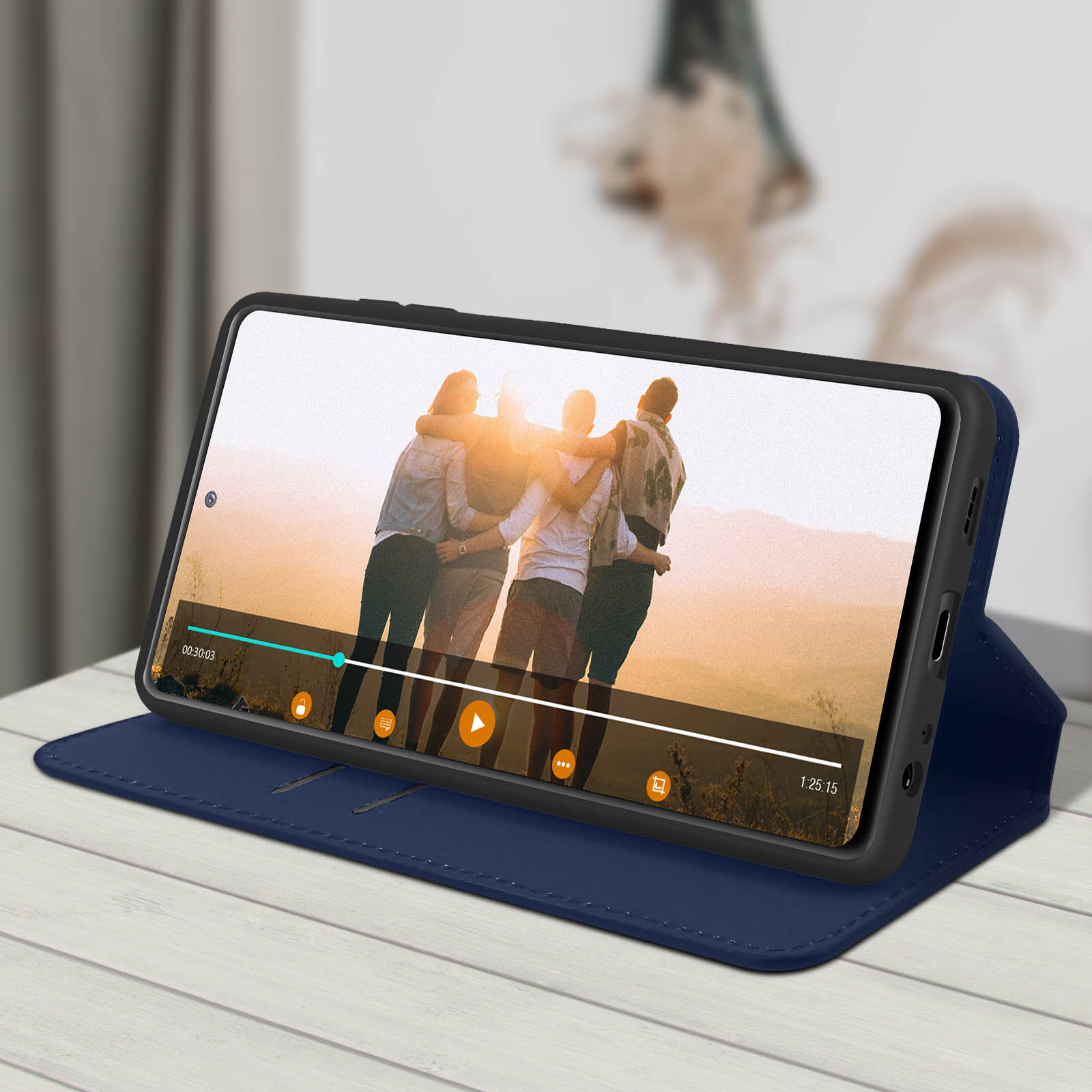 Telefono che mostra il video di un gruppo che si abbraccia. Custodia blu su tavolo di legno con sfondo sfocato.